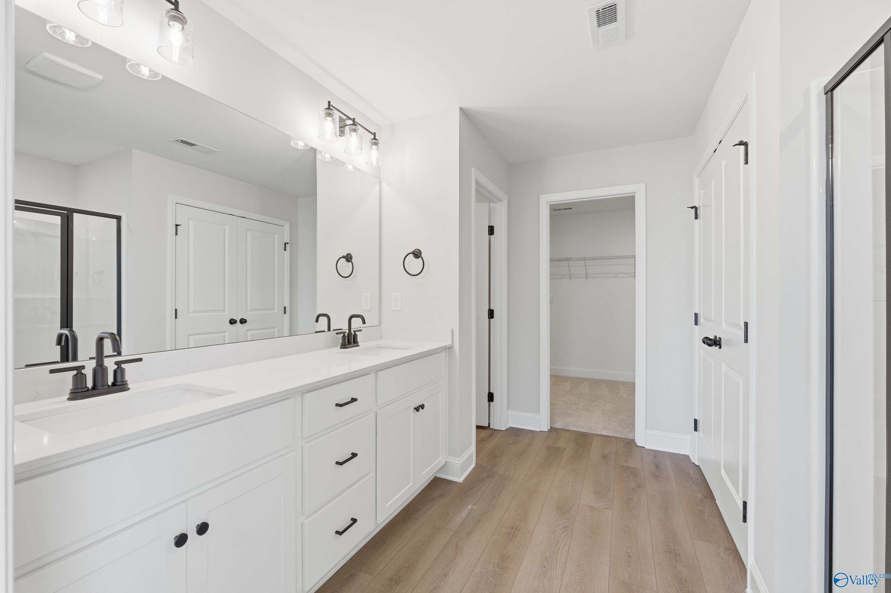Modern master bathroom with double vanity, white shaker cabinets, quartz counters, and walk-in closet in Davidson Homes The Chelsea D, Cullman