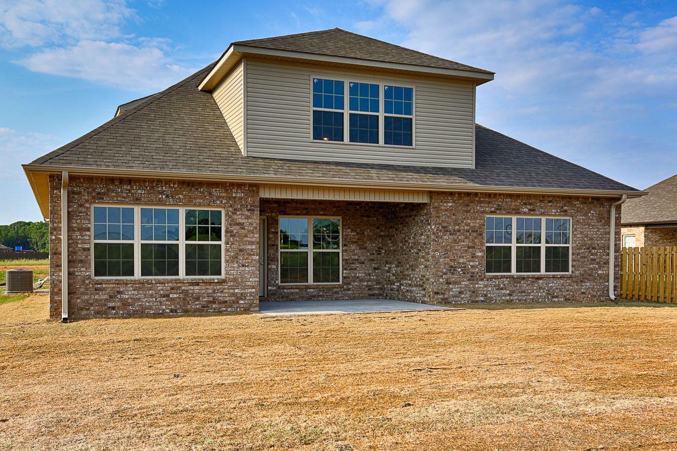 Rear elevation of The Montgomery home by Davidson Homes in Meridianville, AL, with brick siding, large windows, and covered patio