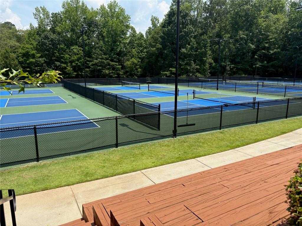 Vibrant blue and green tennis courts with chain-link fences and lush trees in Riverwood, Dallas, Georgia community