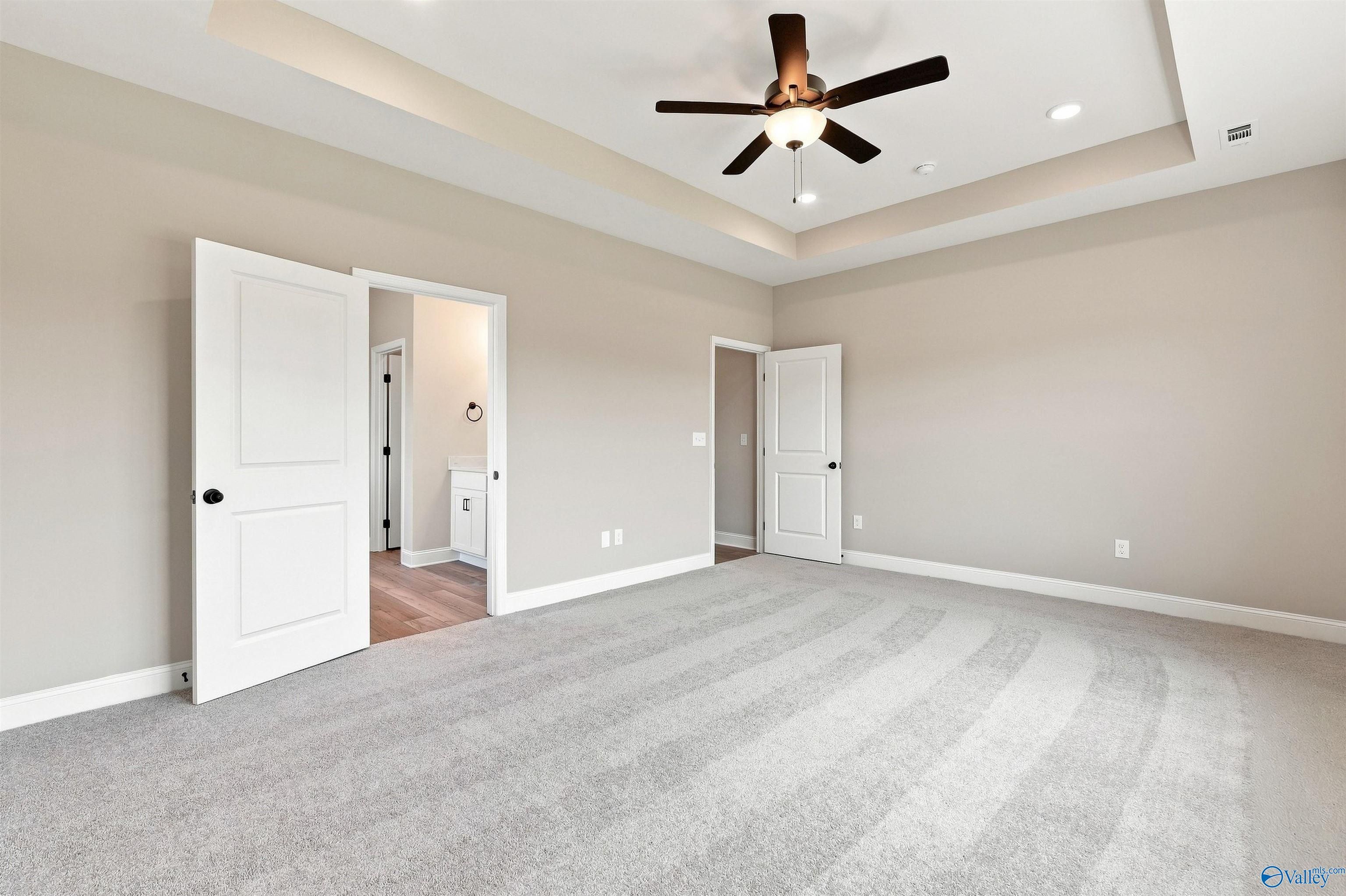 Spacious primary bedroom with tray ceiling and ceiling fan in The Montgomery floor plan at Kendall Downs, Toney, Alabama.