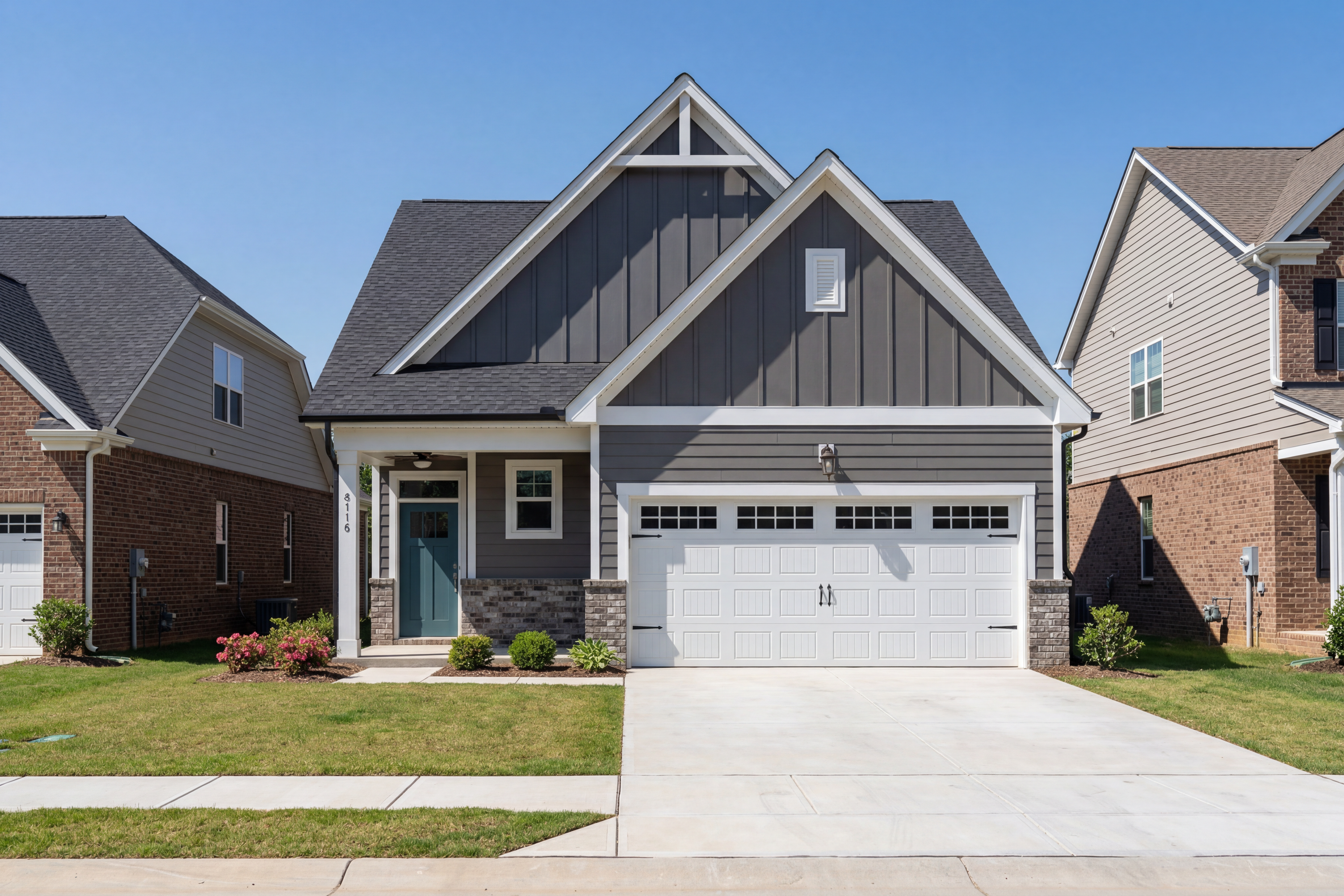 Modern gray craftsman exterior of Carter B single-story home featuring 2-car garage, front porch, and lush landscaping in Lillington NC
