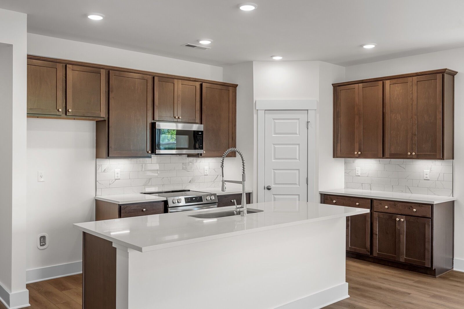 Modern kitchen with white island, dark wood cabinets, and stainless appliances in Davidson Homes Cottonwood E, Gallatin, TN