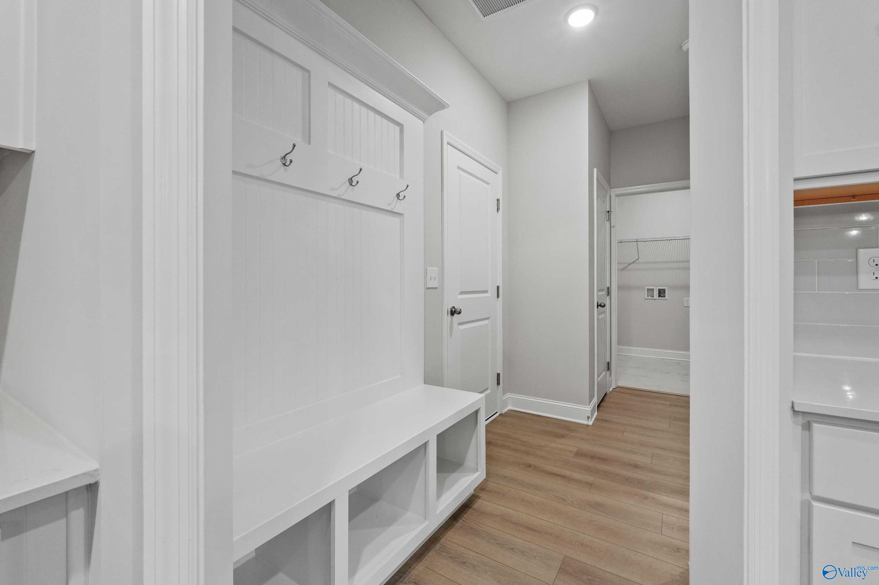 Bright mudroom with white lockers, coat hooks, and built-in bench in Davidson Homes The Lanier, Harvest, Alabama