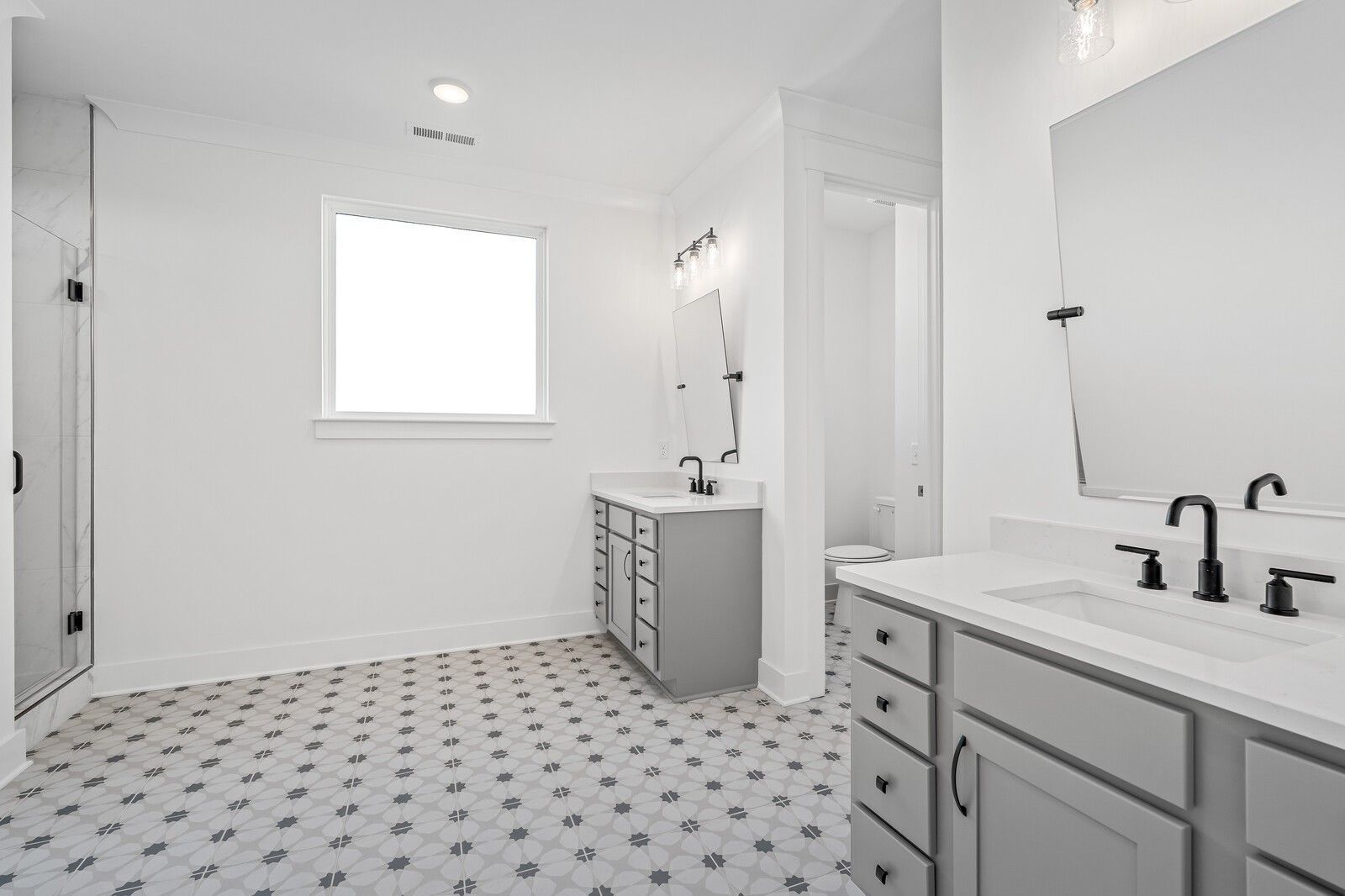 Modern master bathroom with double gray vanity, black faucets, and star-patterned tile floor in Davidson Homes The Alston A, Murfreesboro, TN