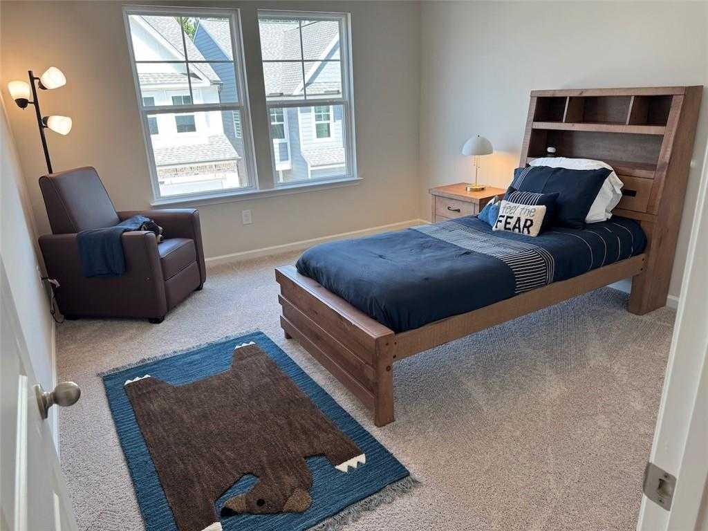 Cozy boy's bedroom with wooden bed, blue bedding, bear rug, and armchair in Davidson Homes The Cary A, Kennesaw, Georgia