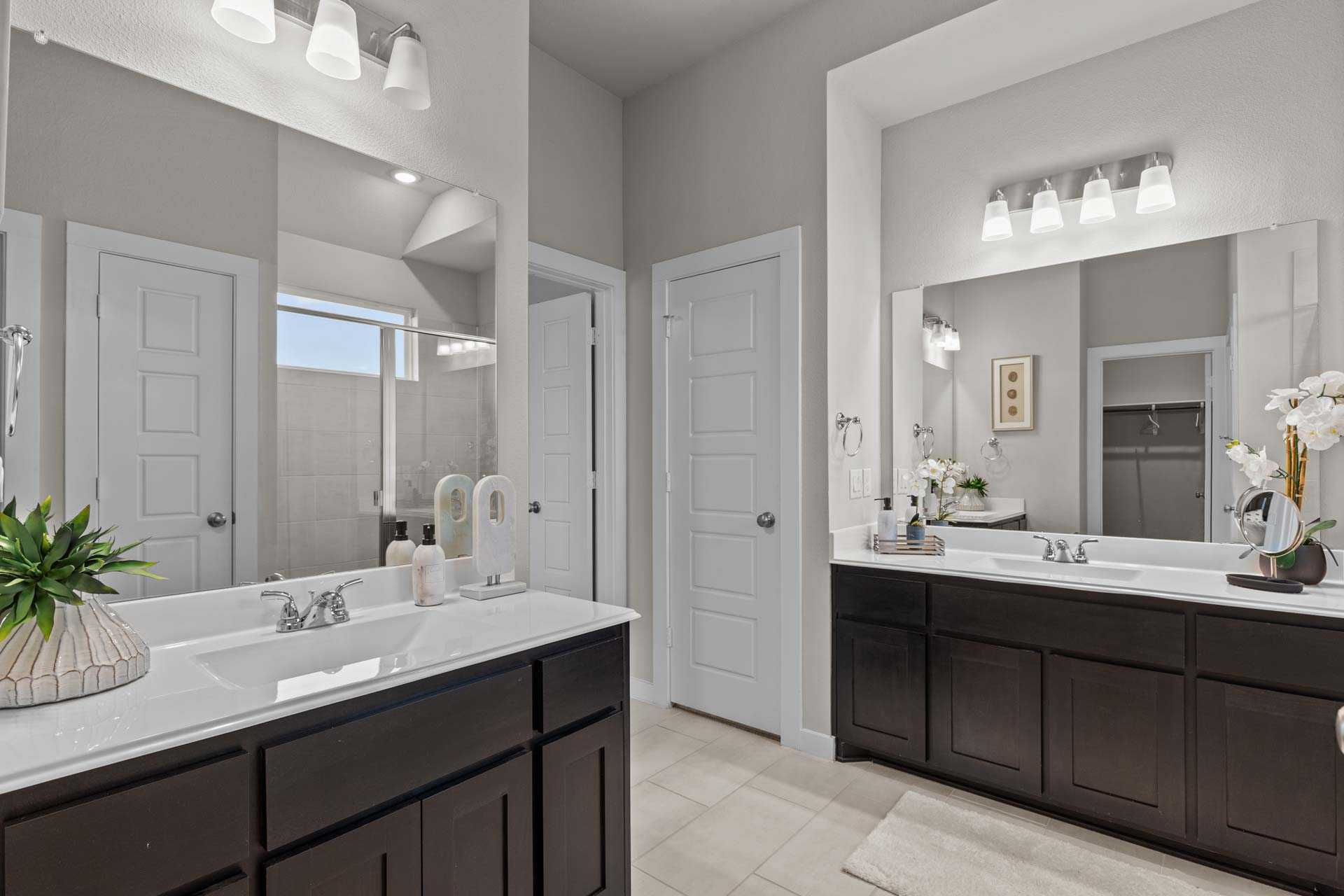 Spacious master bathroom in The Collin B featuring double vanity, dark cabinets, mirrors, and orchids