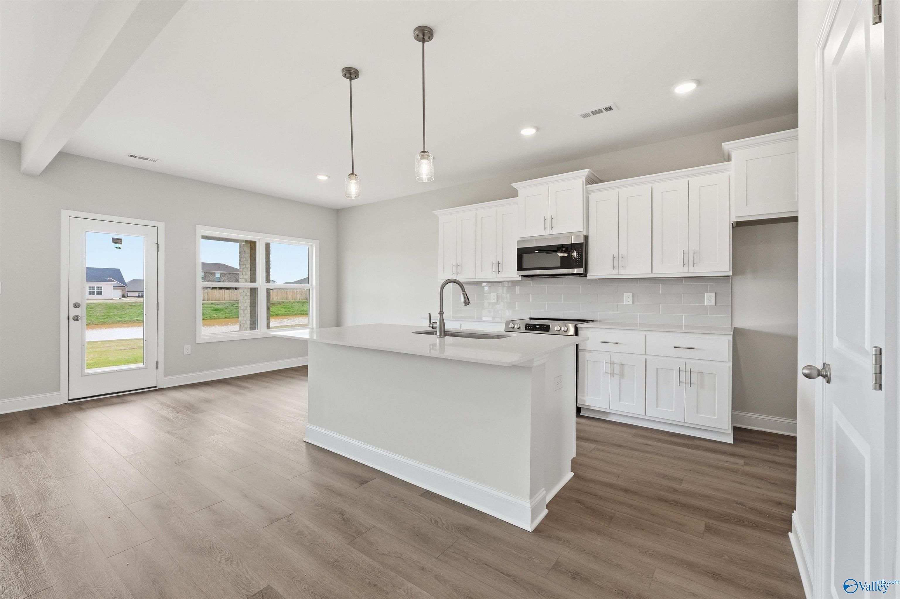 Modern kitchen with white cabinets, island, and stainless appliances in The Shelby D floor plan, Evergreen Mill, Madison.