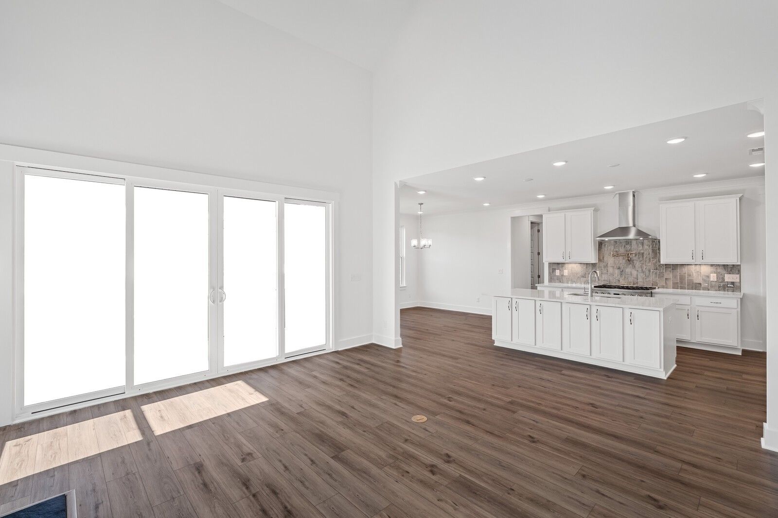 Bright open-concept great room with hardwood floors, large sliding doors, and modern white kitchen island in Davidson Homes The Hawkins, Murfreesboro