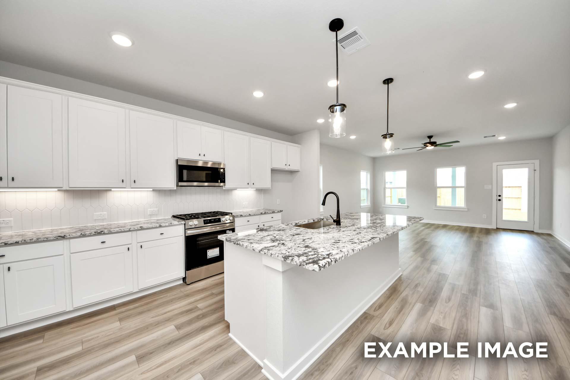 Modern open-concept kitchen in The Sorrento with white cabinetry, granite island, and stainless steel appliances.