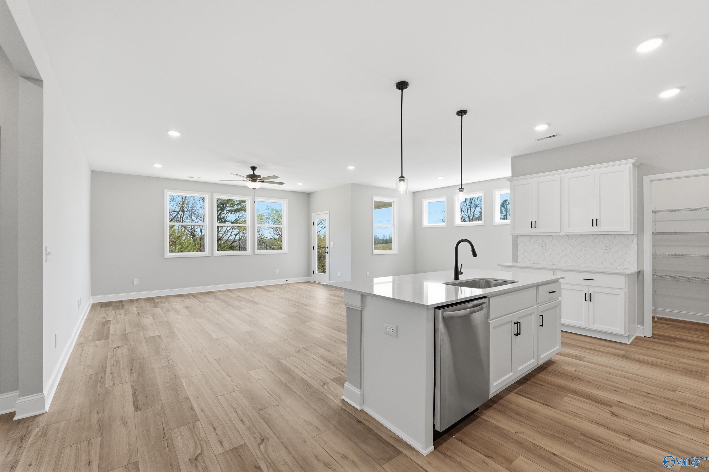 Open-concept kitchen with white island, stainless sink, and pendant lights in The Laurel K 3-bedroom home, Cullman, Alabama