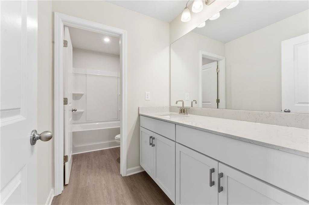 Modern bathroom featuring white shaker cabinets, quartz vanity, frameless walk-in shower in Davidson Homes The Ash B, Dallas, GA
