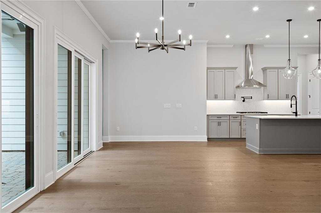 Bright open-concept kitchen and dining with gray island, hardwood floors, sliding doors to patio in Davidson Homes Seaside B, Woodstock GA