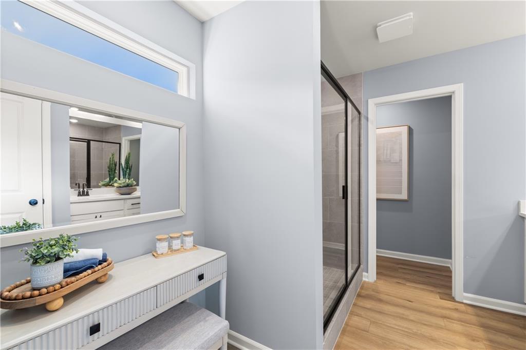 Spacious master bathroom with white double vanity, glass shower, and light blue walls in Davidson Homes The Burton C, Canton, Georgia
