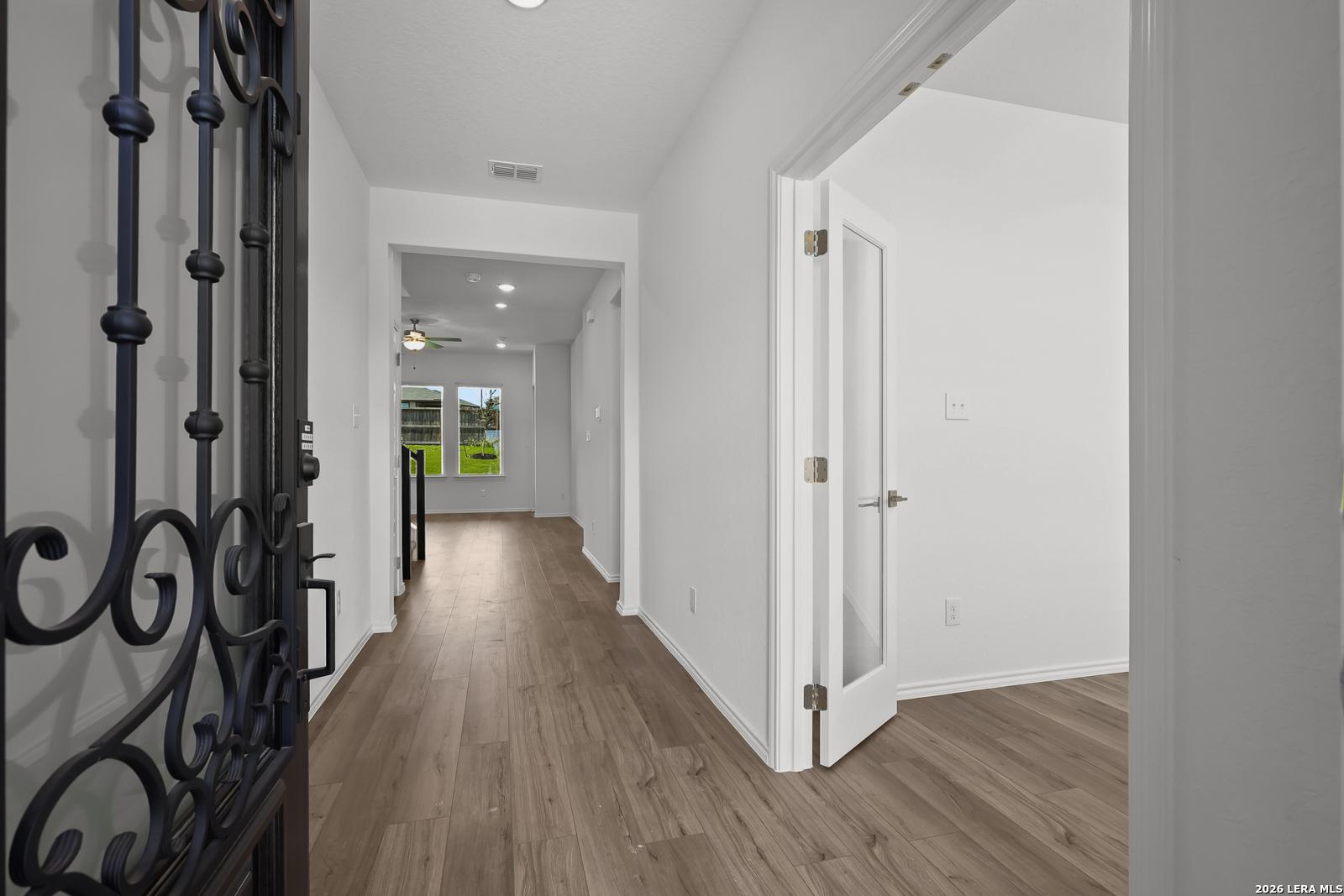 Elegant foyer with wrought iron gate, hardwood floors, and staircase in Davidson Homes The Sequoia B, Comanche Ridge, San Antonio