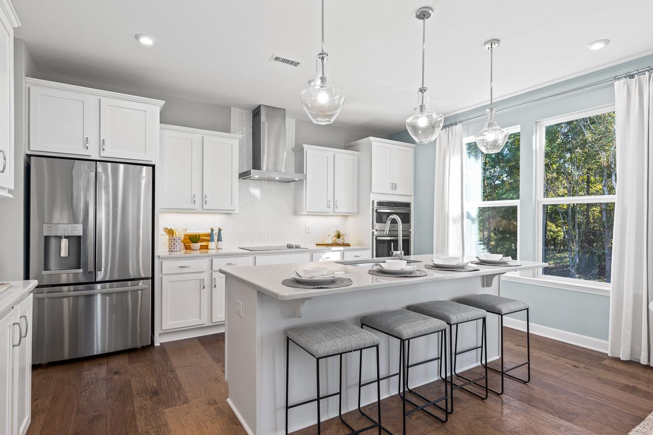 Modern gourmet kitchen in The Hemlock A featuring white cabinetry, quartz island, and stainless steel appliances.