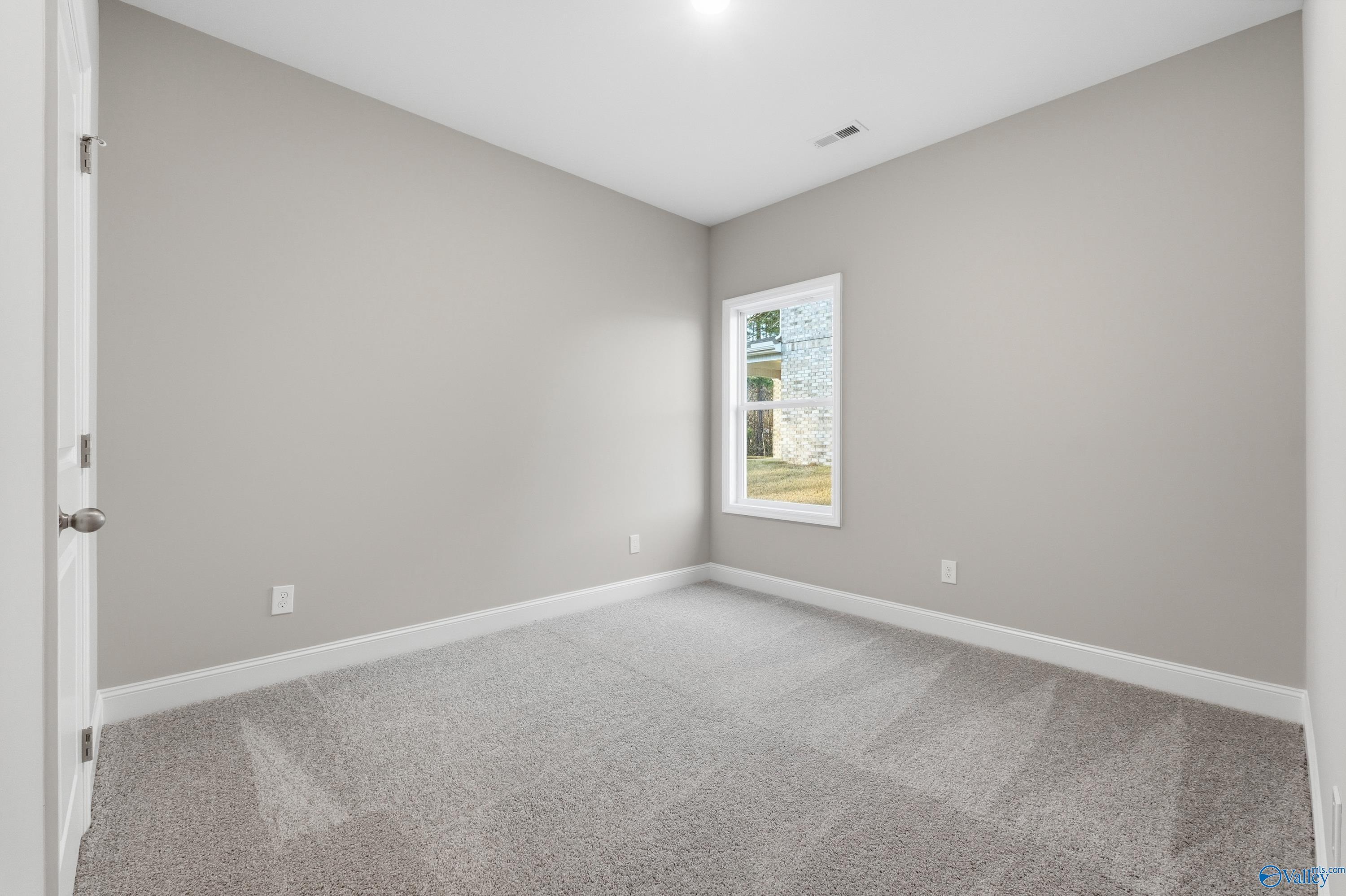 Bright secondary bedroom featuring light gray walls, neutral carpet, and large window in The Asheville floor plan, Arab, Alabama