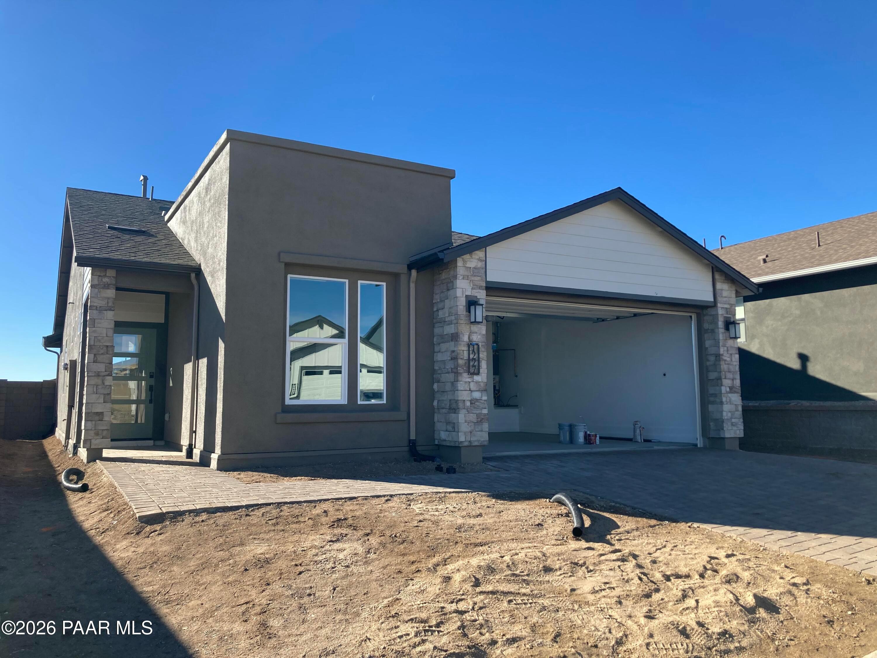 Modern gray stucco single-story home with open 2-car garage, stone accents, and large windows in South Ranch, Prescott, Arizona