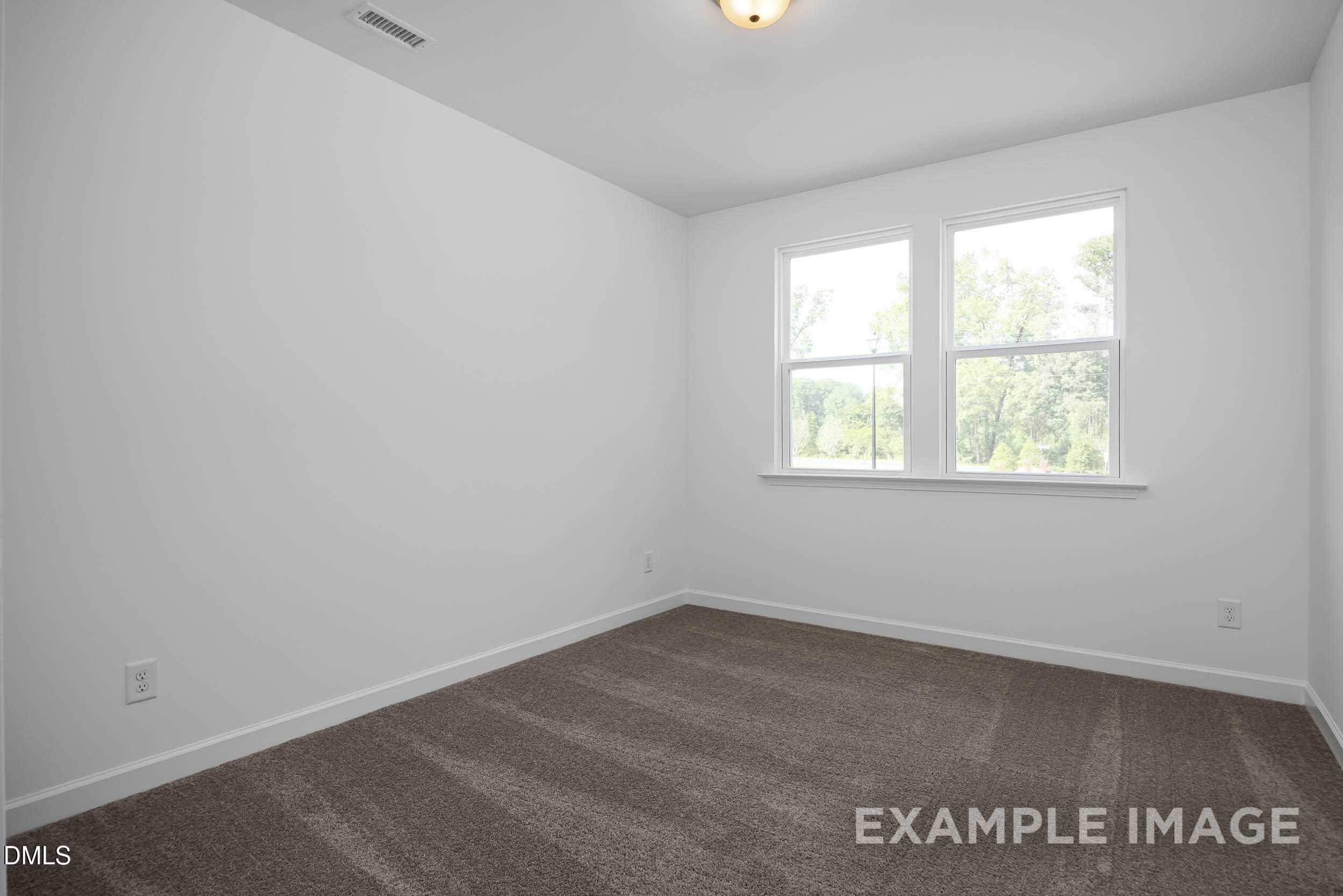 Bright bedroom with white walls, large double windows, and brown carpet in Davidson Homes The Willow D, Zebulon, NC