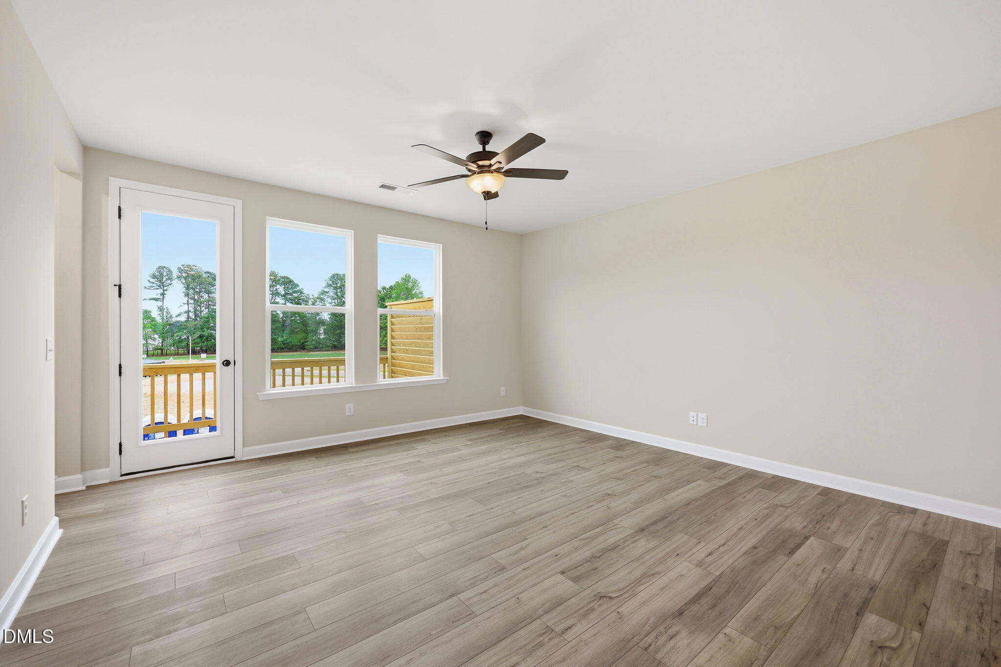 Bright living area with wood-style flooring and deck access in The Mitchell floor plan at Camden Park, Knightdale, NC.
