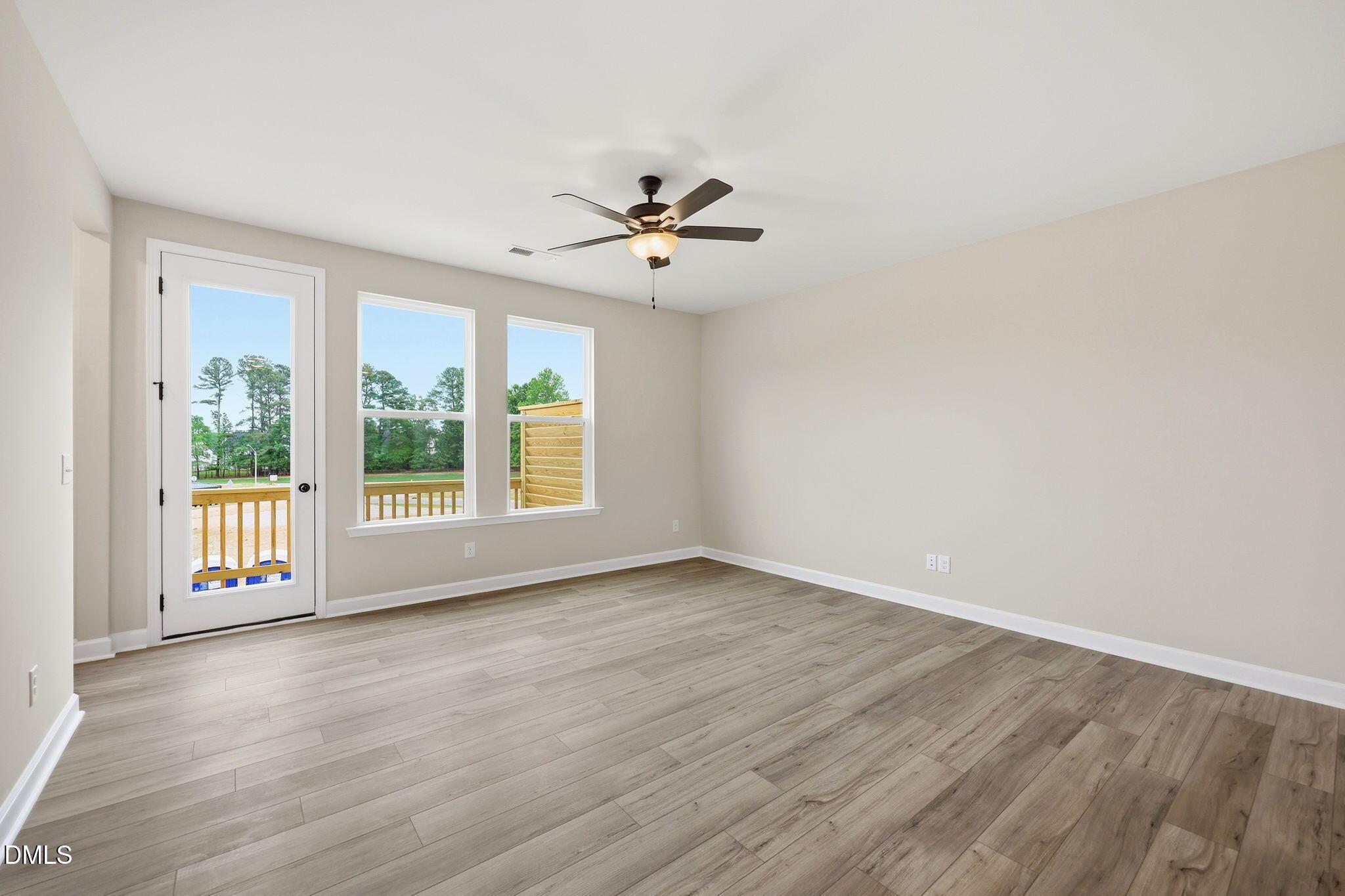 Bright living area with wood-style flooring and deck access in The Mitchell floor plan at Camden Park, Knightdale, NC.