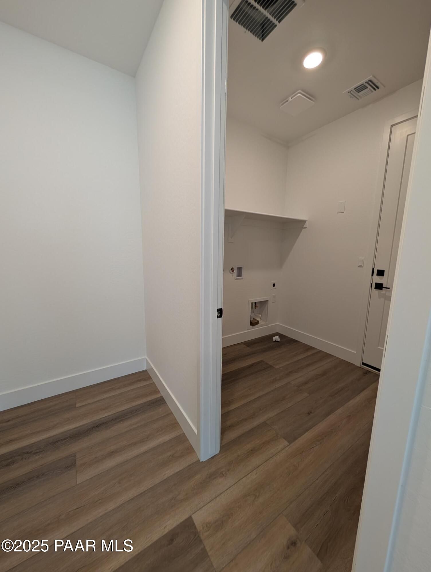 Spacious laundry room with utility sink, washer dryer hookups, open shelving, and hardwood floors in Davidson Homes The Sheridan II F, Prescott, Arizona