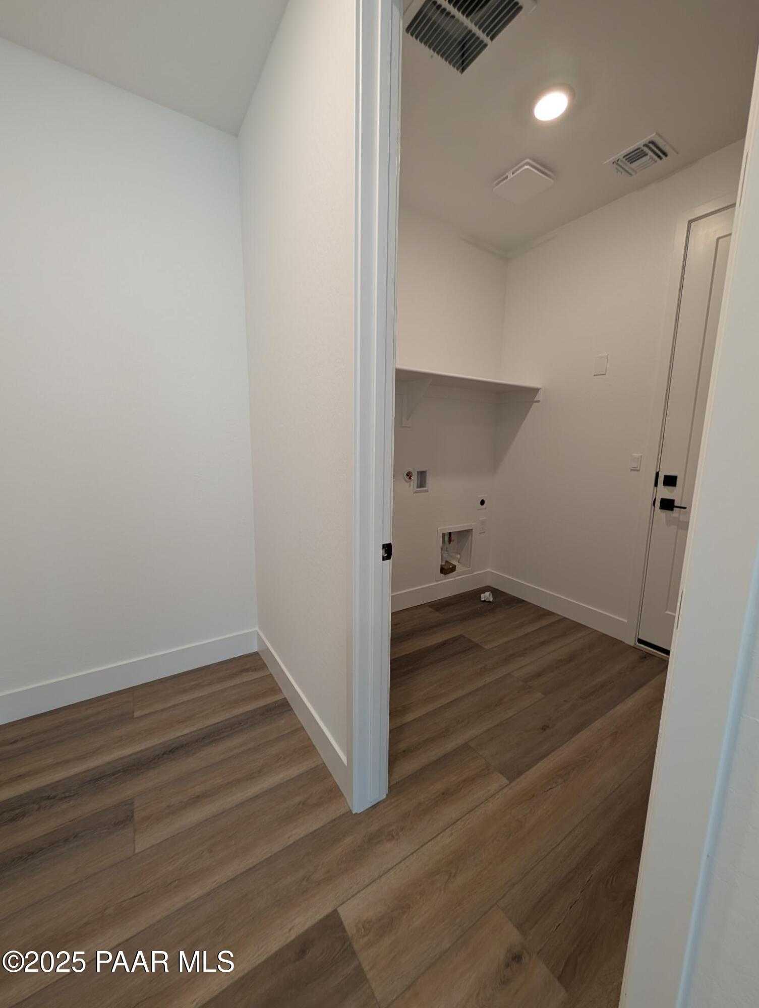 Spacious laundry room with utility sink, washer dryer hookups, open shelving, and hardwood floors in Davidson Homes The Sheridan II F, Prescott, Arizona