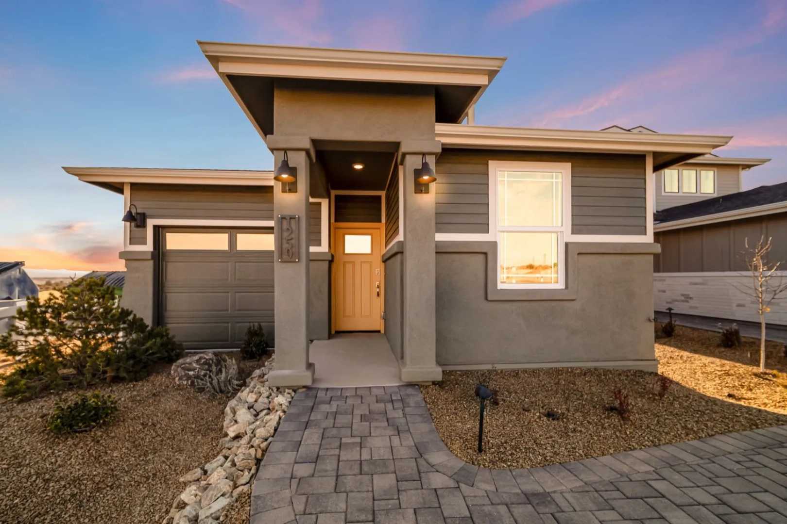 Contemporary gray stucco home exterior at South Ranch Southern Collection in Prescott AZ with paver walkway, desert rocks, and sunset sky