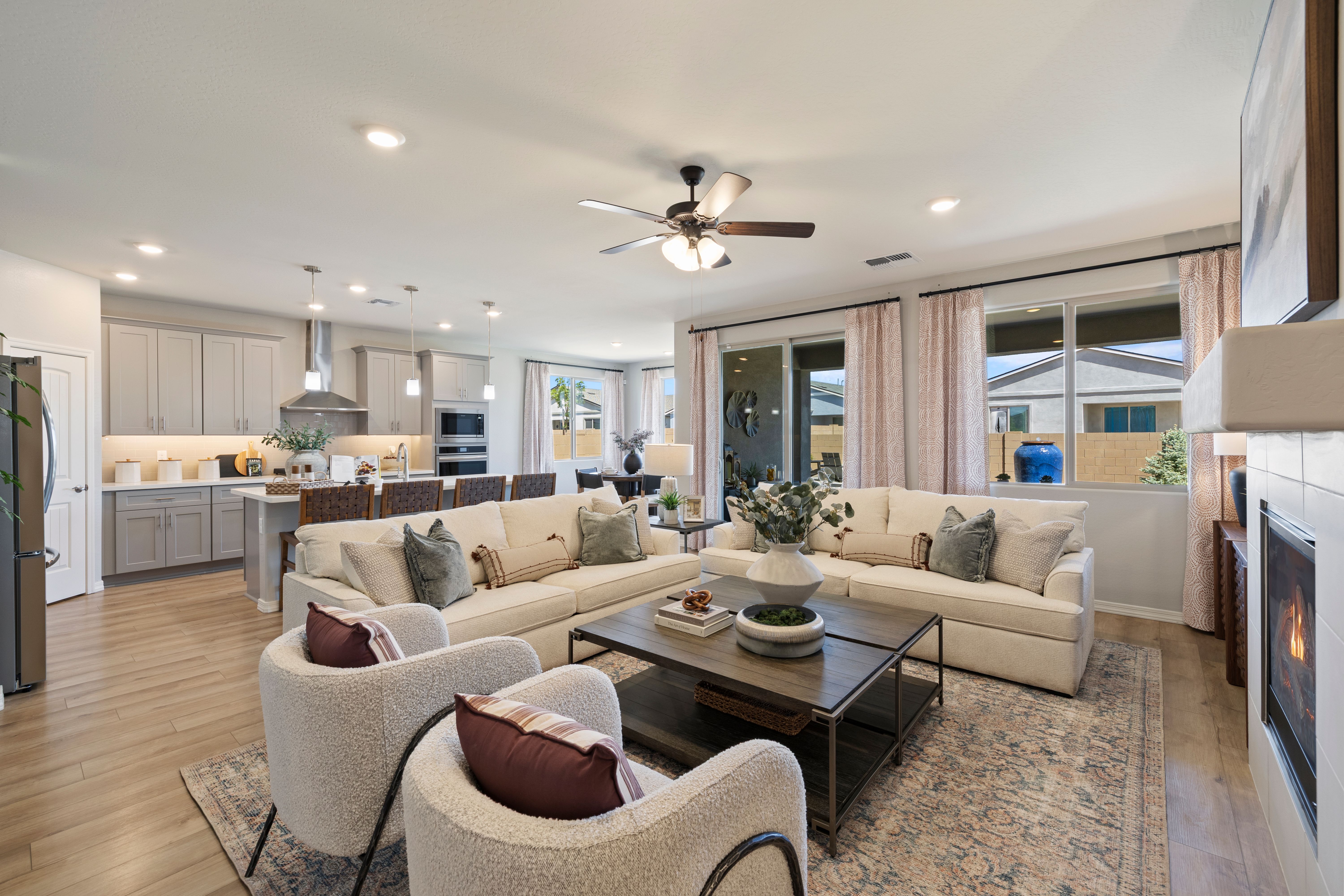 Spacious open-concept living room and kitchen in North Ridge at Pronghorn Ranch, Prescott Valley AZ with beige sofas, hardwood floors, fireplace