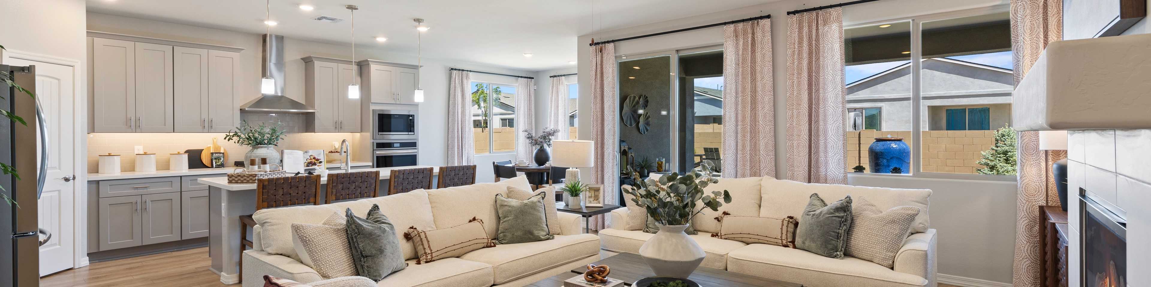 Spacious open-concept living room and kitchen in North Ridge at Pronghorn Ranch, Prescott Valley AZ with beige sofas, hardwood floors, fireplace