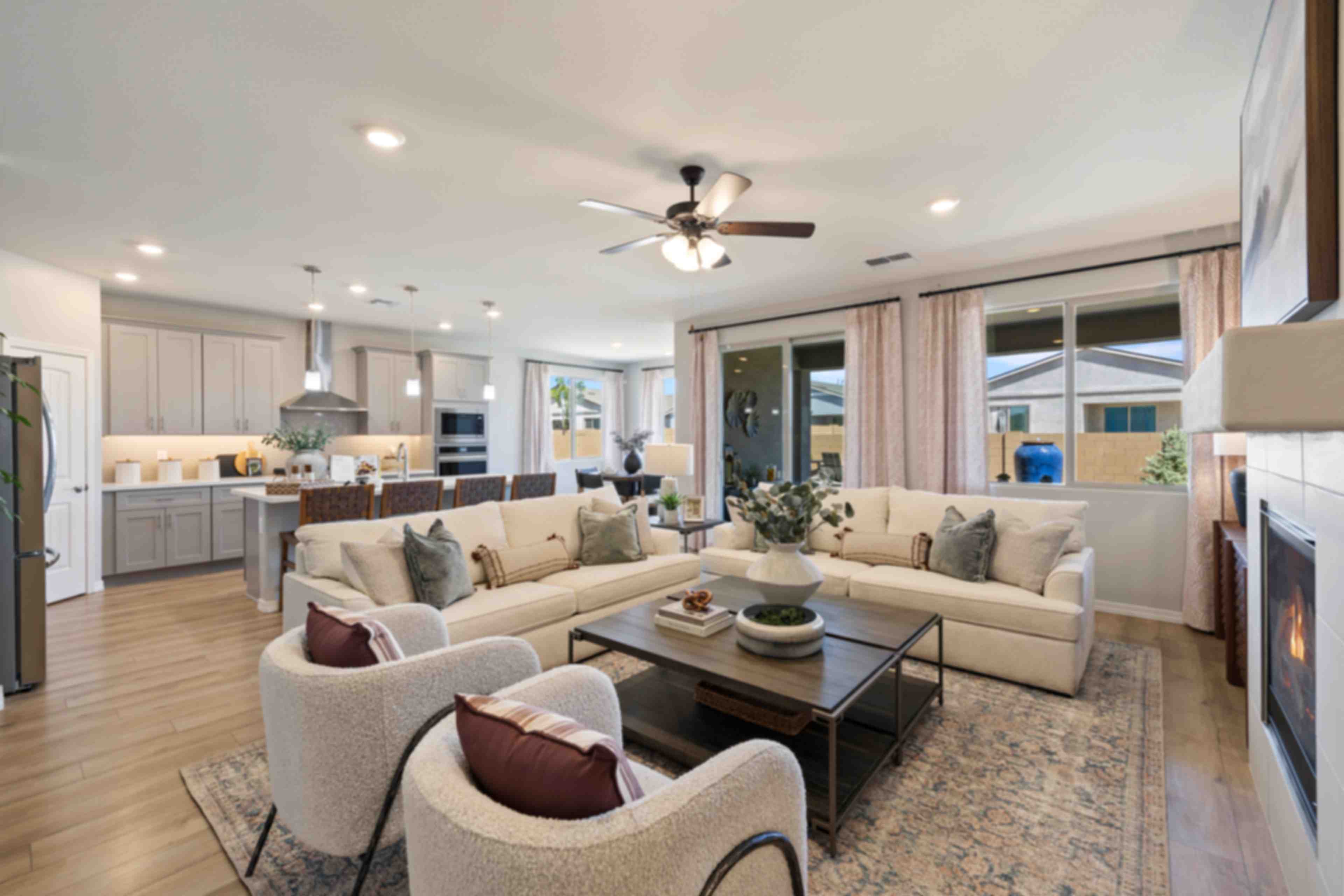 Spacious open-concept living room and kitchen in North Ridge at Pronghorn Ranch, Prescott Valley AZ with beige sofas, hardwood floors, fireplace