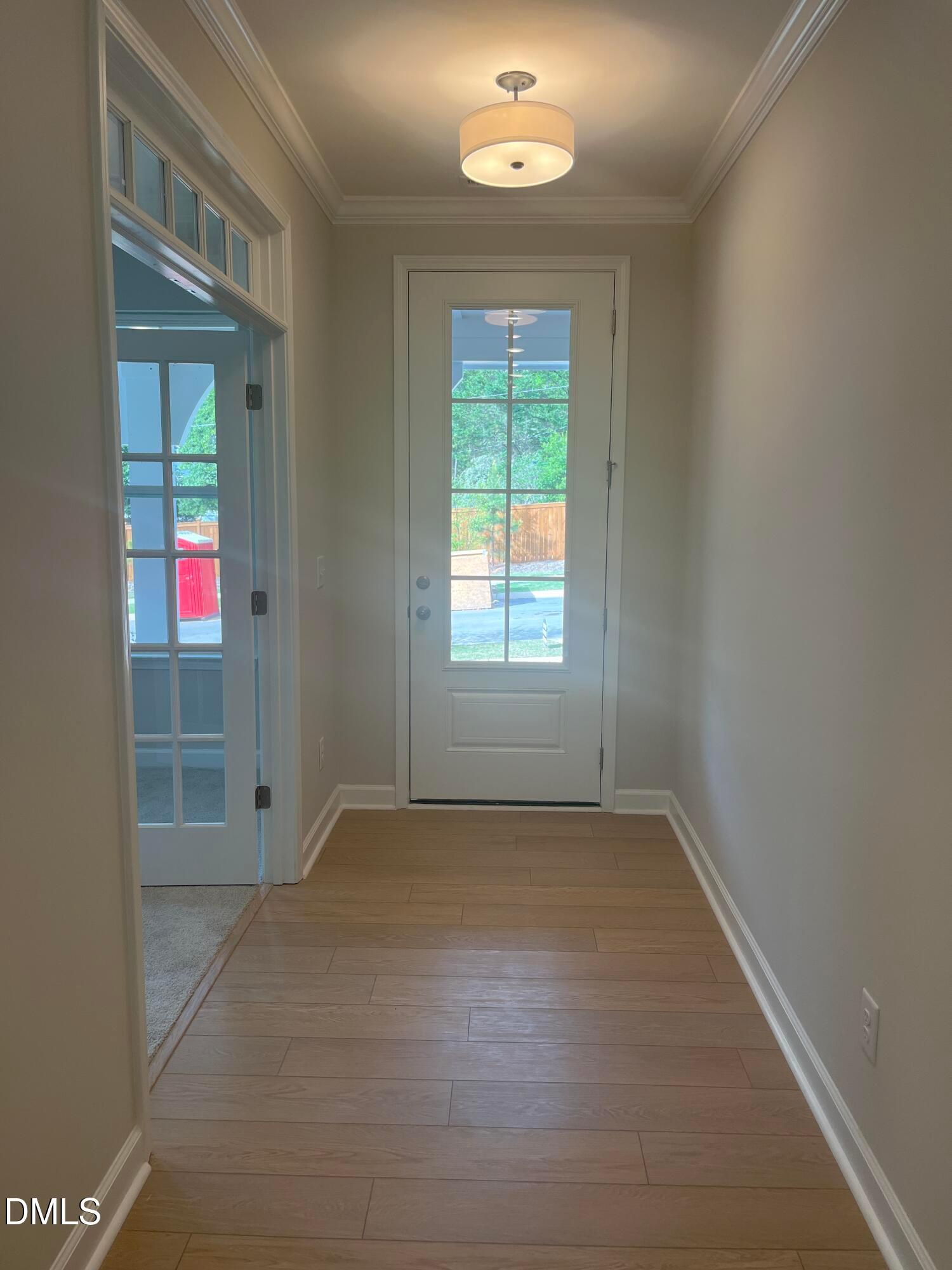 Bright entryway hallway with oak hardwood floors, glass door to backyard, and chandelier in The Ashport L home, Wake Forest, NC