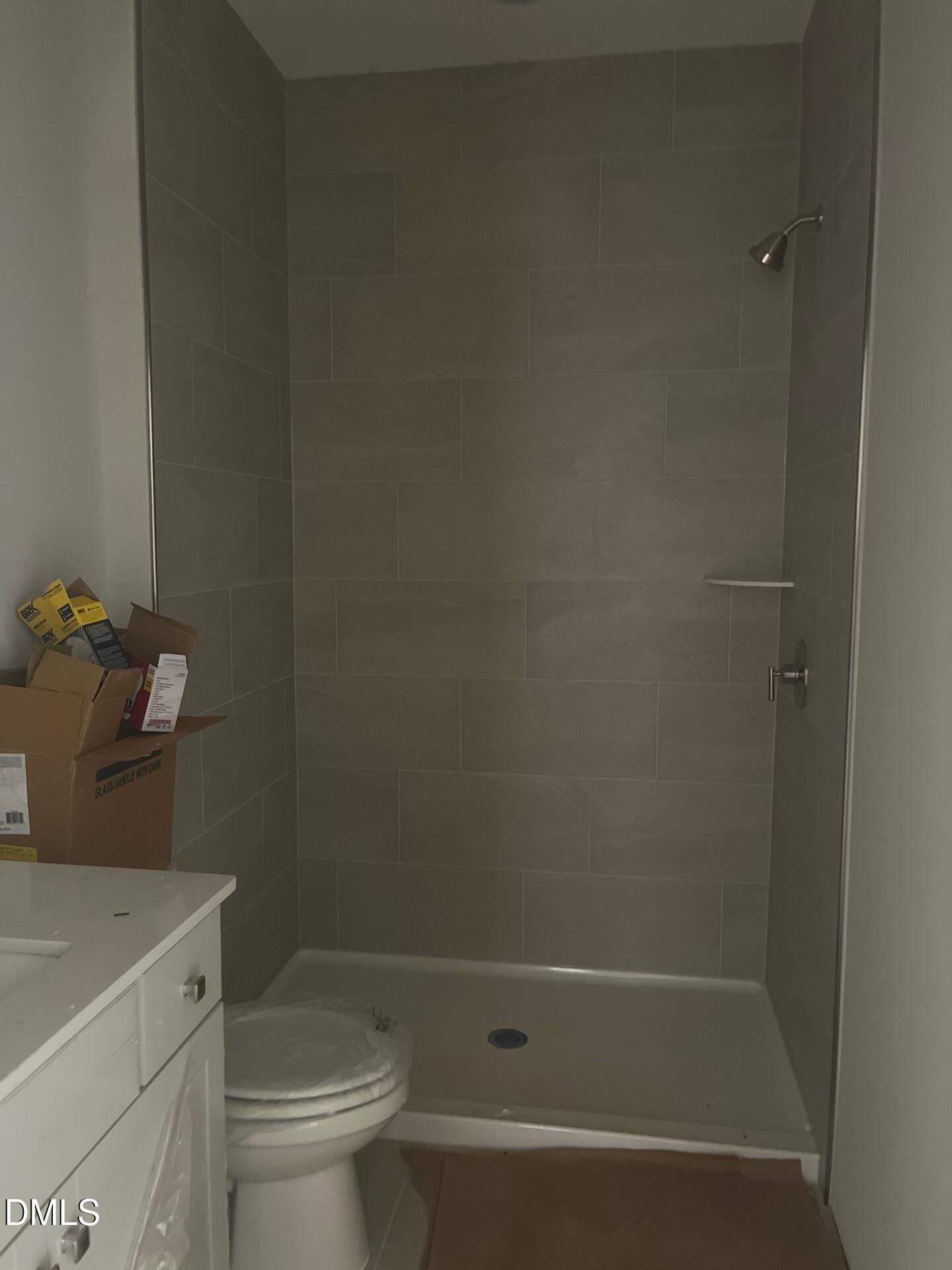 Modern gray-tiled walk-in shower, white vanity, and toilet in primary bathroom of 5-bedroom Ashport G home, Wake Forest, NC