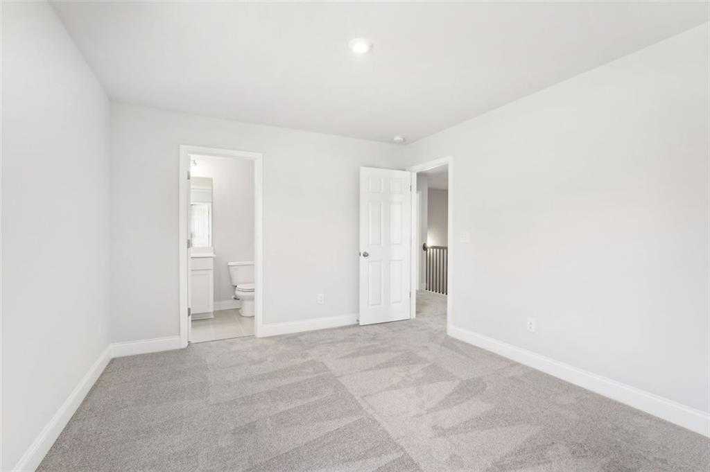 Bright secondary bedroom with en-suite bath, white walls, gray carpet in Davidson Homes The Hickory C, Hoschton, GA