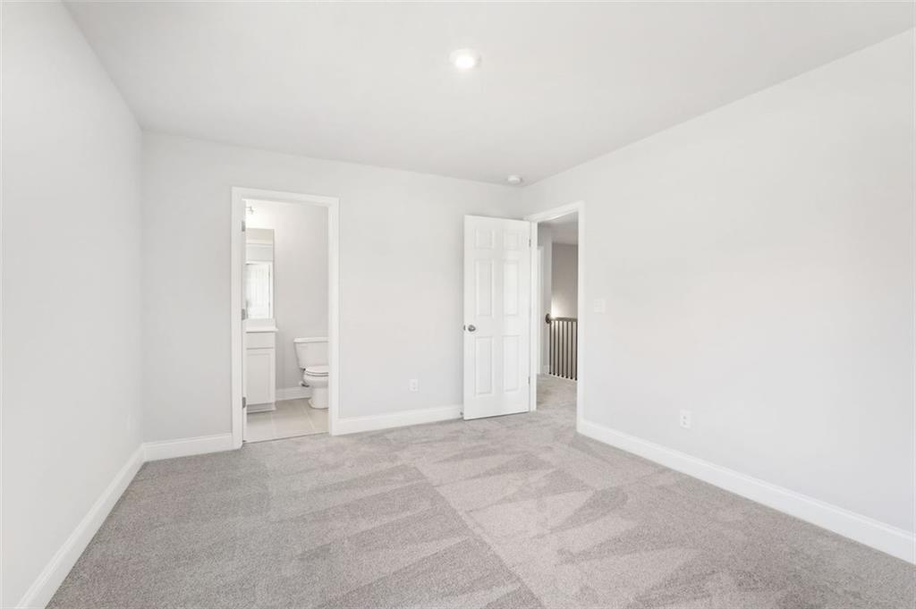 Bright secondary bedroom with en-suite bath, white walls, gray carpet in Davidson Homes The Hickory C, Hoschton, GA