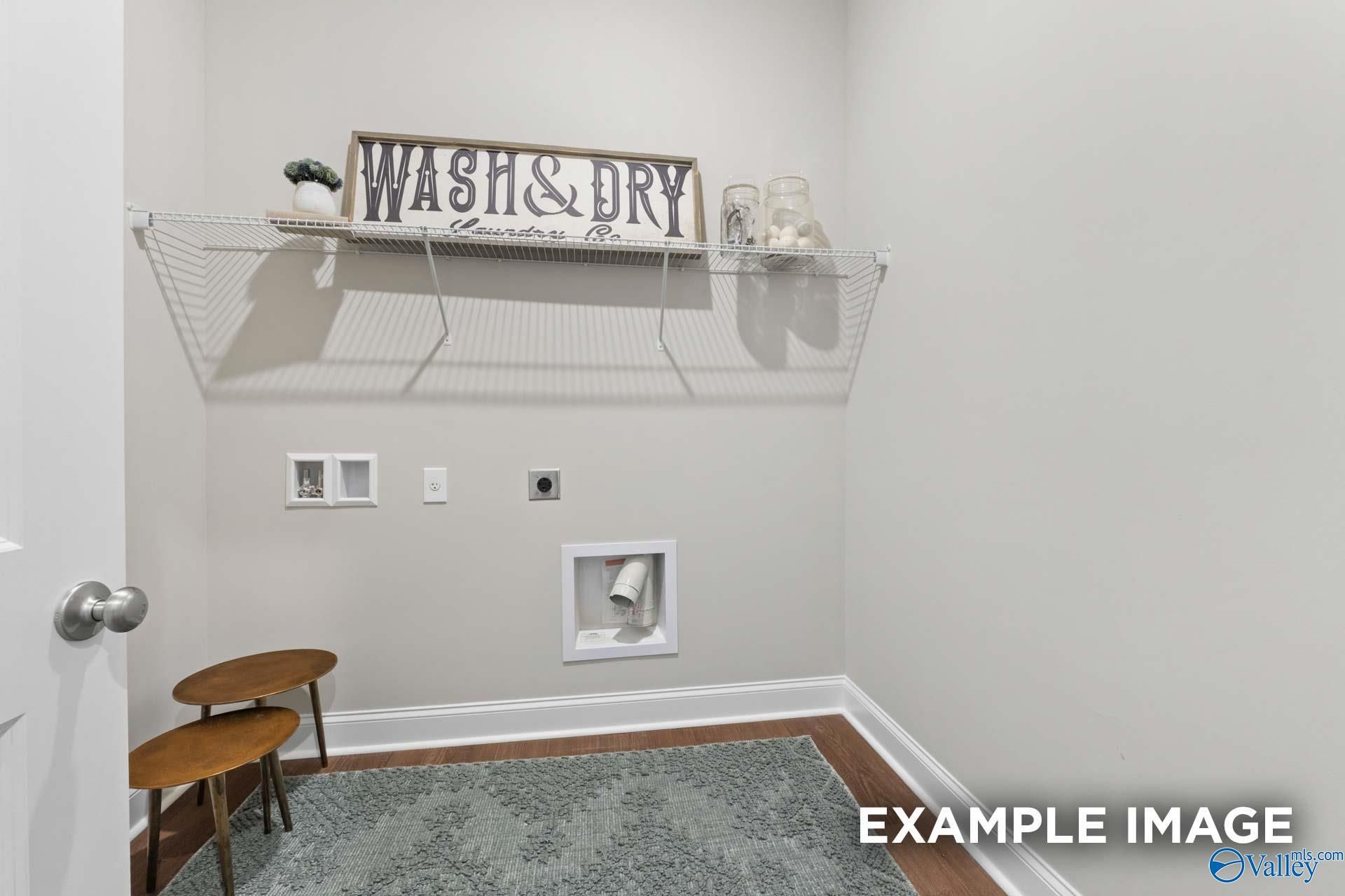 Functional laundry room featuring wire shelving, Wash & Dry sign, utility hookups, and hardwood floors in Evermore Homes The Haven E, Owens Cross Roads, AL