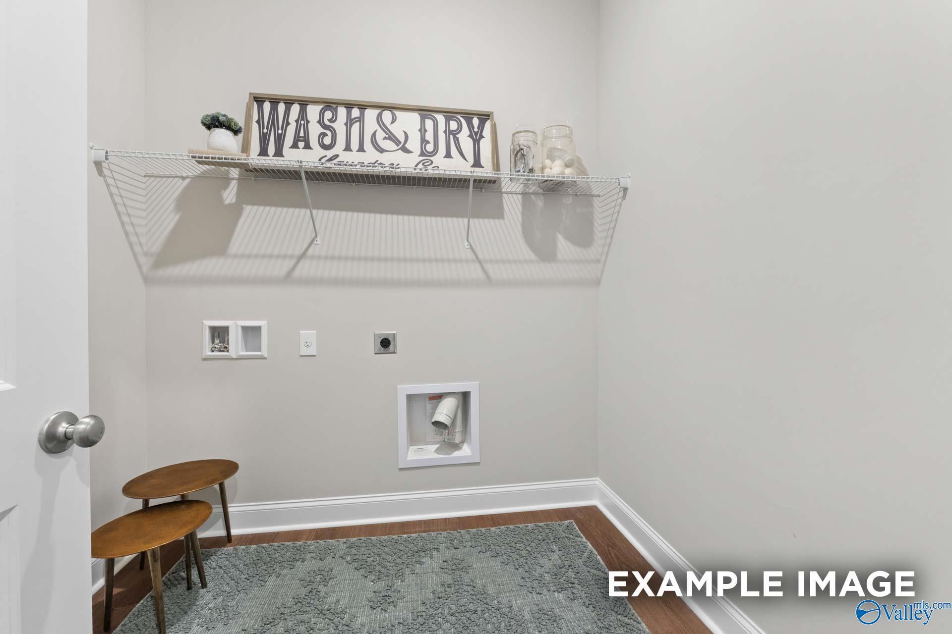 Functional laundry room featuring wire shelving, Wash & Dry sign, utility hookups, and hardwood floors in Evermore Homes The Haven E, Owens Cross Roads, AL