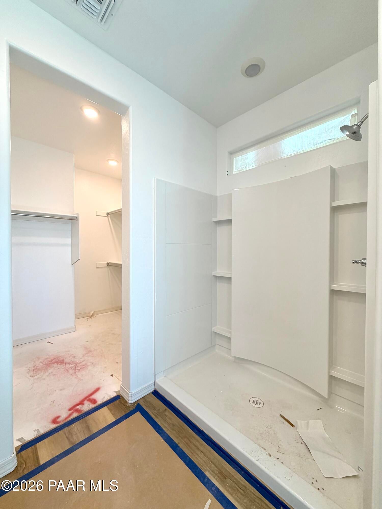 White walk-in shower with built-in shelving and clerestory window beside walk-in closet in Davidson Homes Marietta C, Prescott AZ