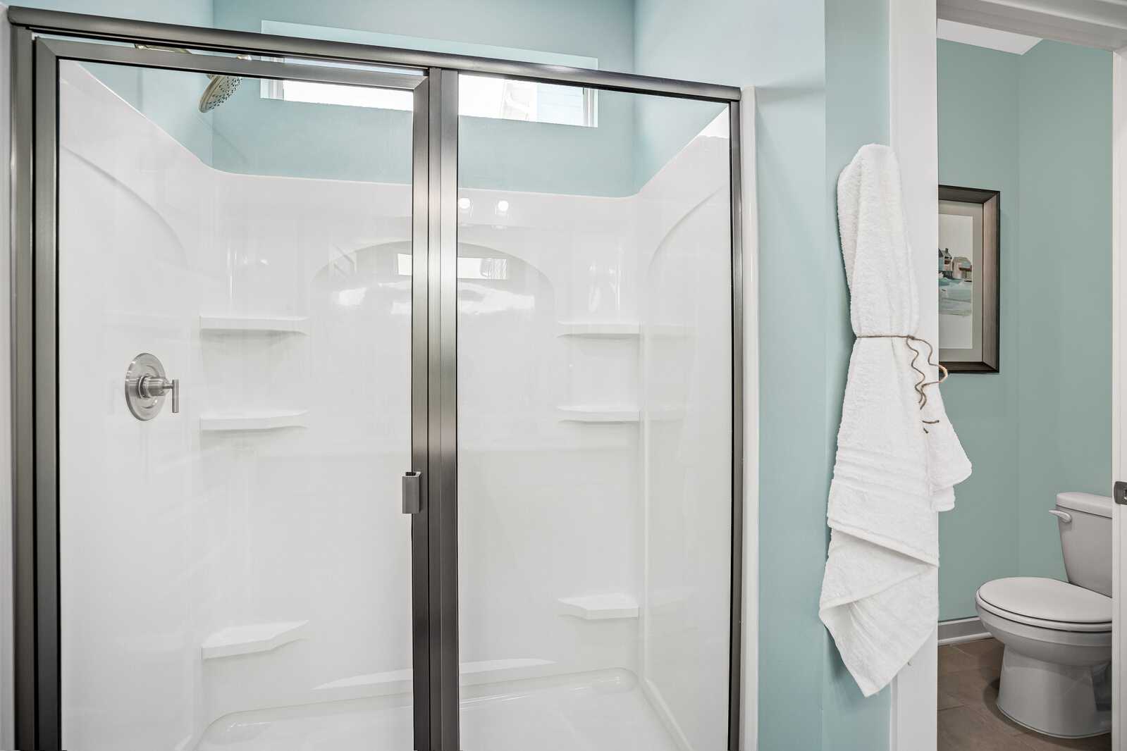 Modern bathroom at Sage Farms in White House TN featuring glass shower enclosure, white tiles, and turquoise walls