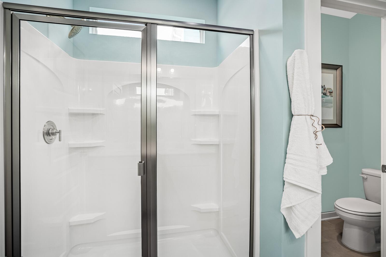 Modern bathroom at Sage Farms in White House TN featuring glass shower enclosure, white tiles, and turquoise walls