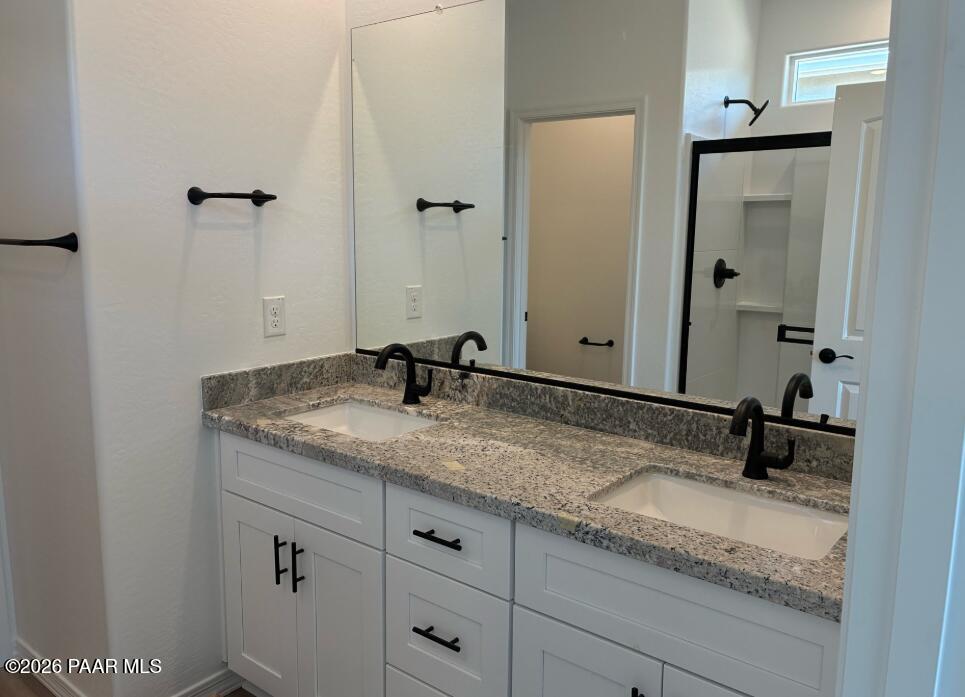 Dual vanity bathroom with granite countertops, white shaker cabinets, and matte black fixtures in Davidson Homes The Newport A, Prescott
