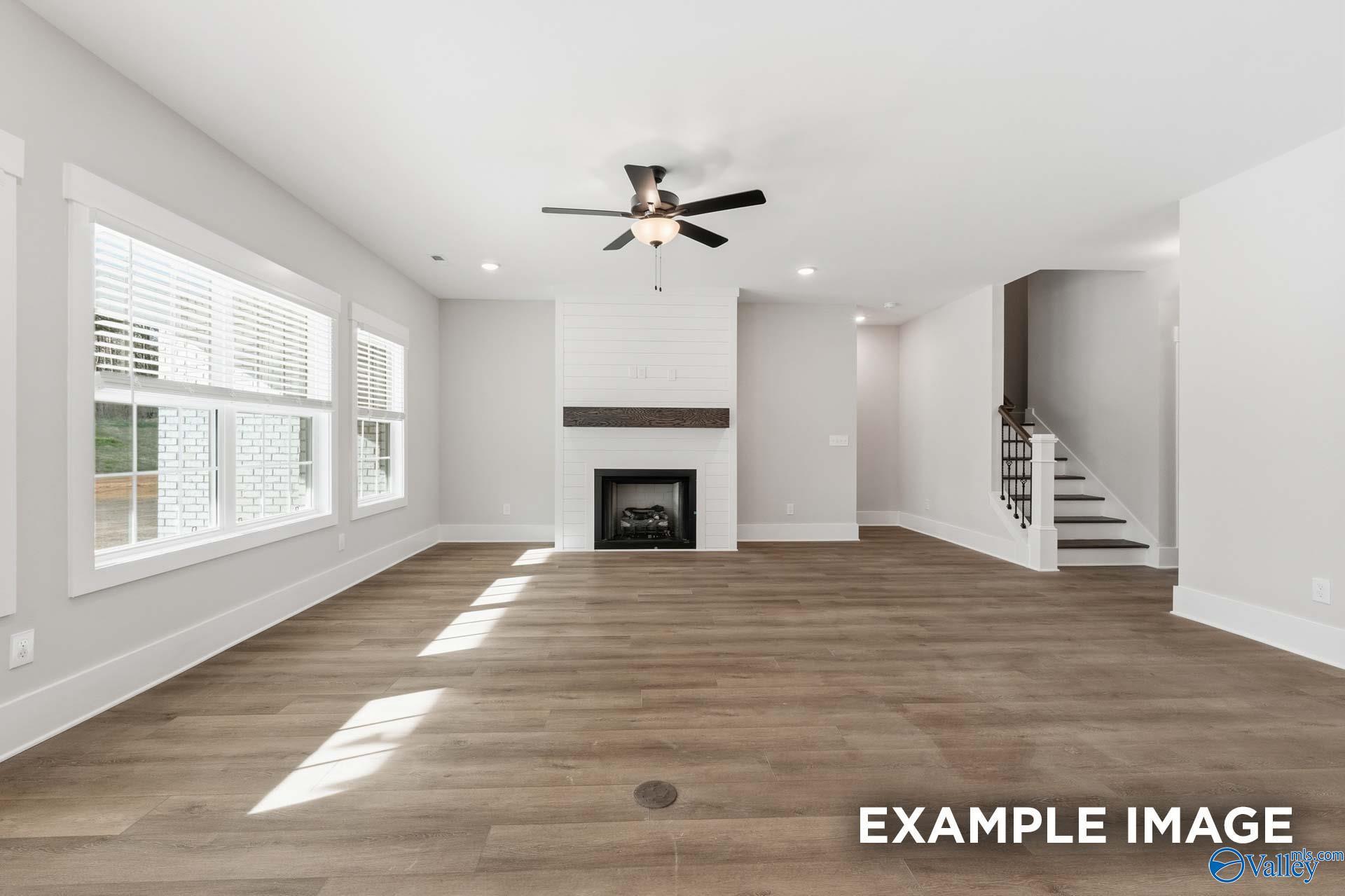 Spacious living room with shiplap fireplace and wood floors in The Rockford floor plan by Davidson Homes in Briercreek.