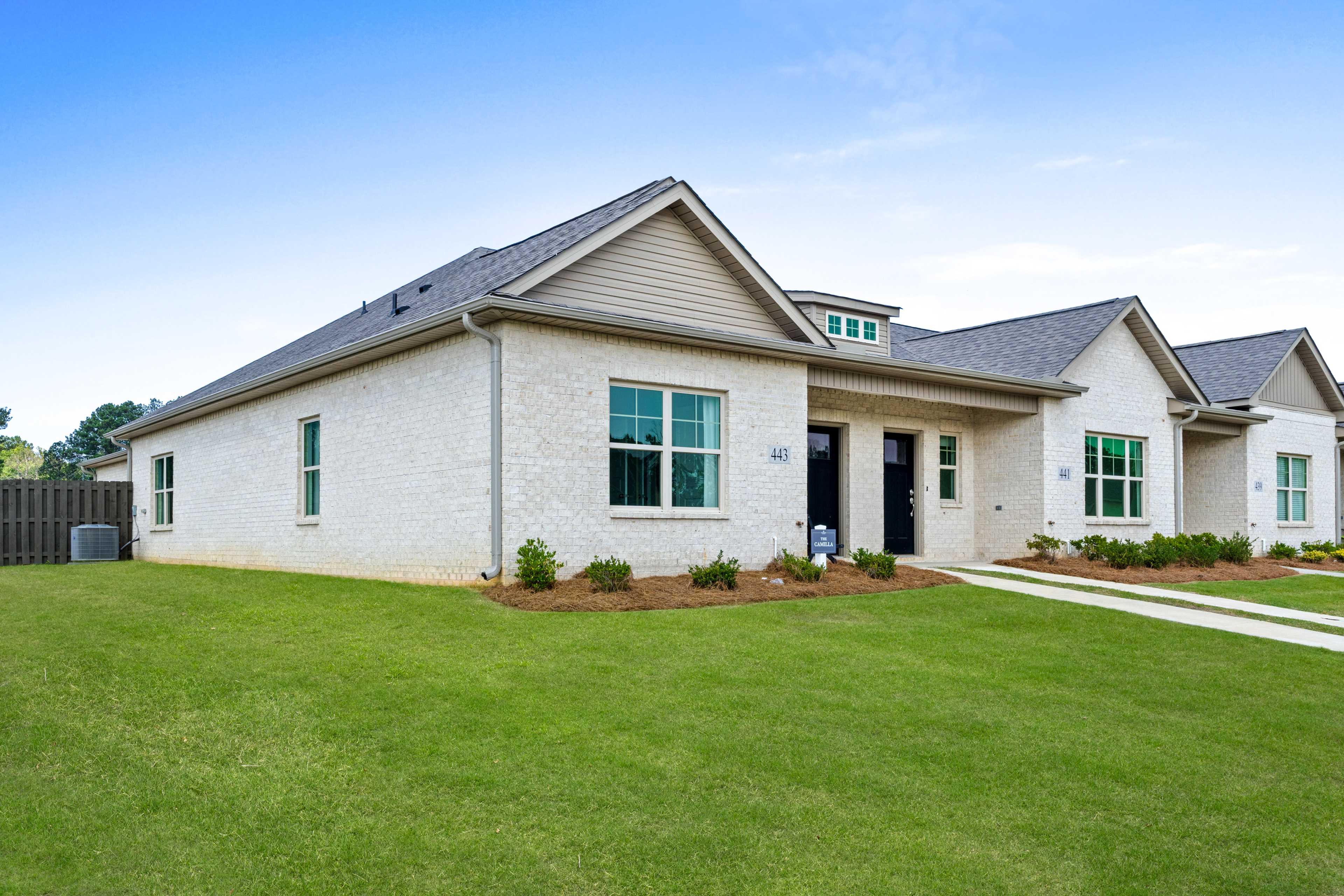 Modern white brick homes at The Retreat at Cain Park in Hartselle AL with gray roofs, large windows, and lush green lawns