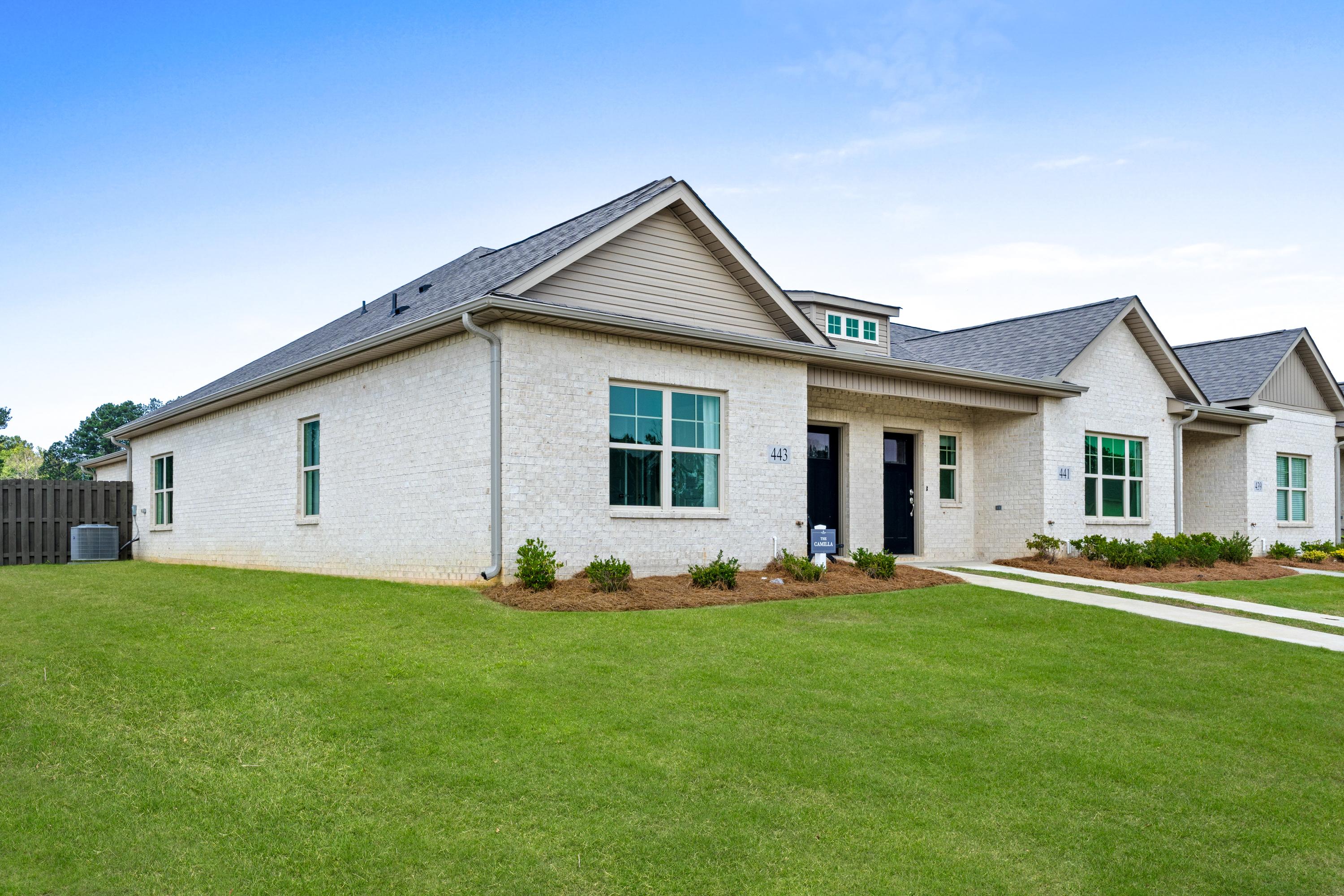 Modern white brick homes at The Retreat at Cain Park in Hartselle AL with gray roofs, large windows, and lush green lawns