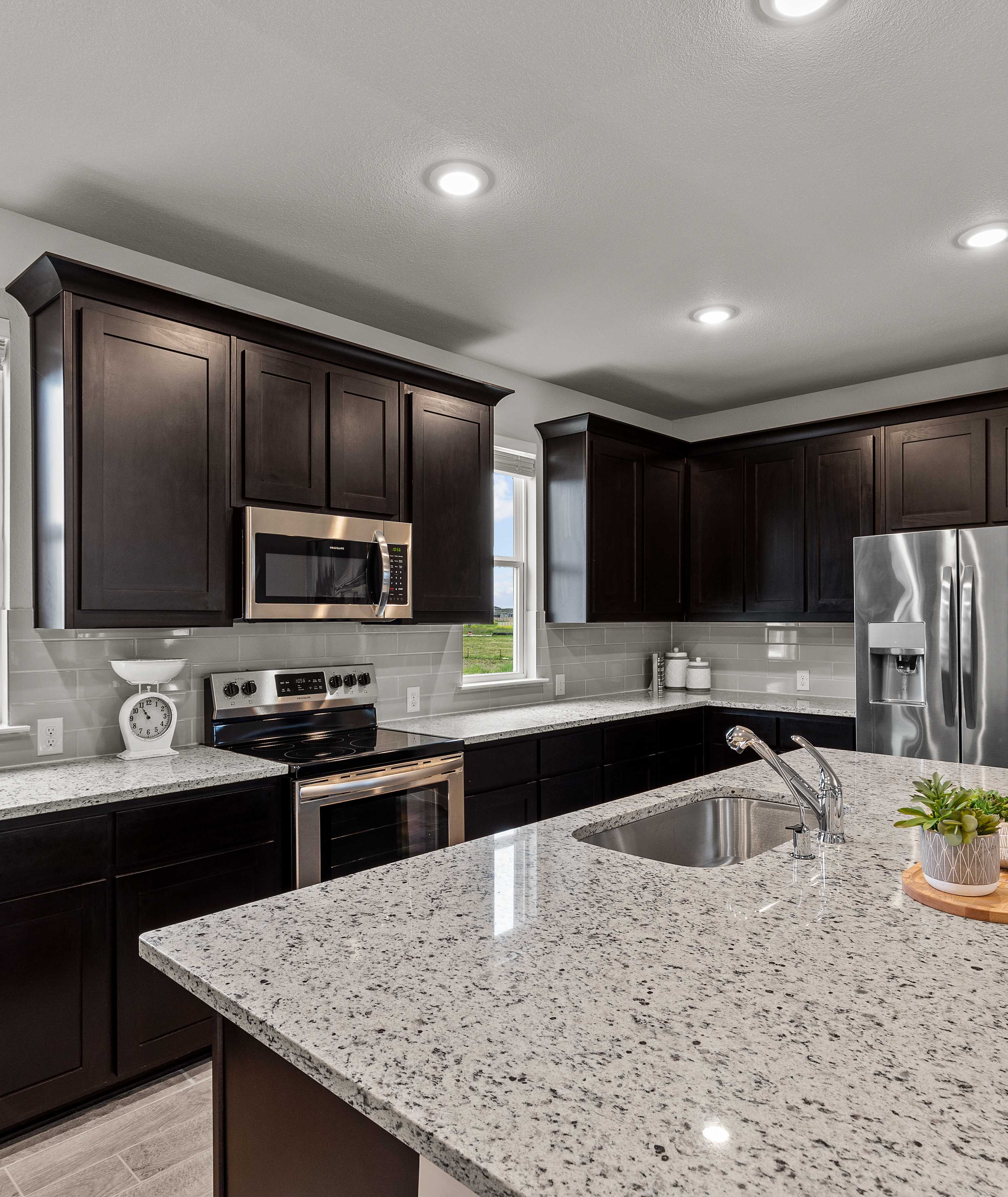 Modern kitchen with dark cabinets, granite island, stainless steel appliances at Hannah Heights in Seguin, Texas