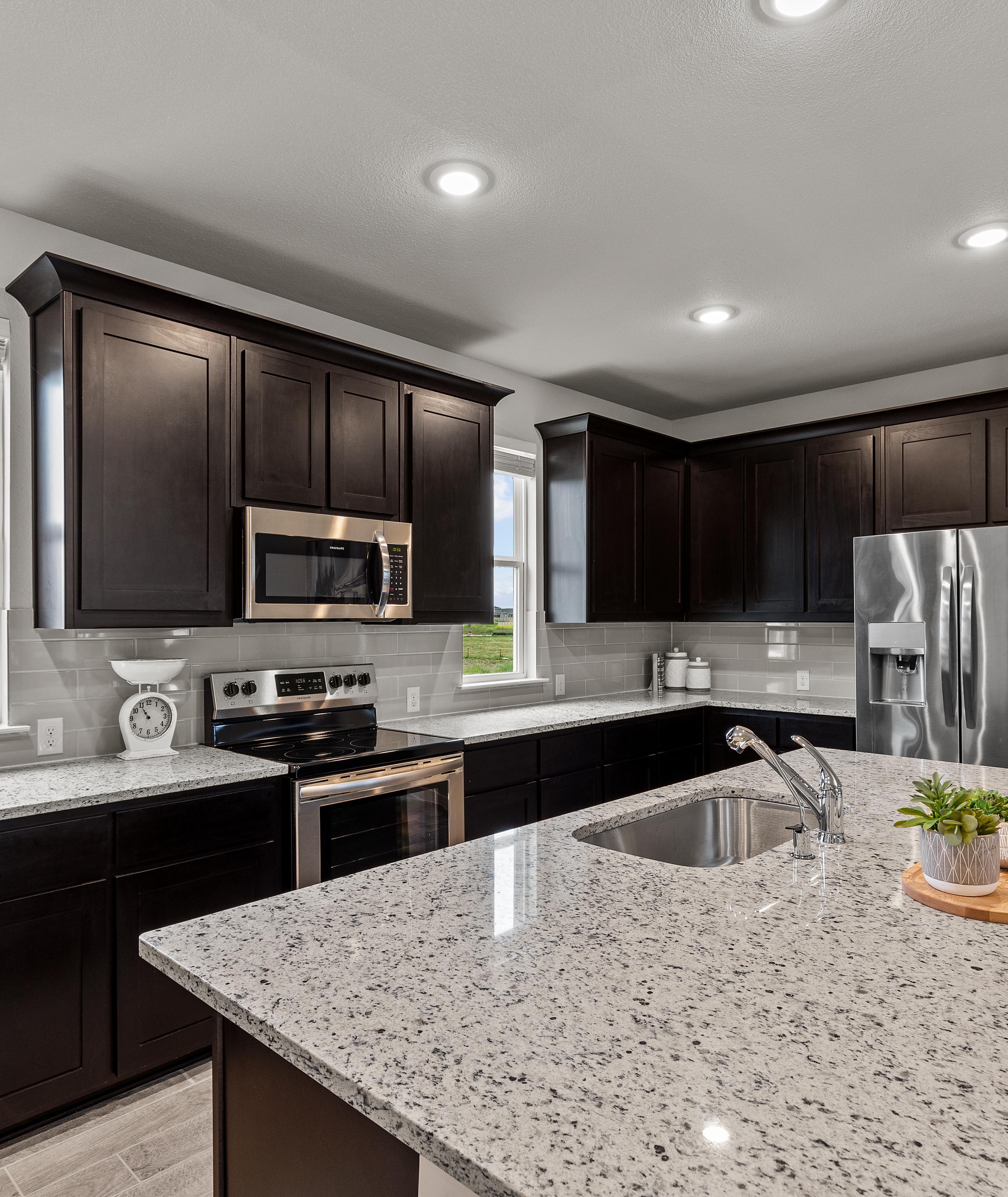 Modern kitchen with dark cabinets, granite island, stainless steel appliances at Hannah Heights in Seguin, Texas