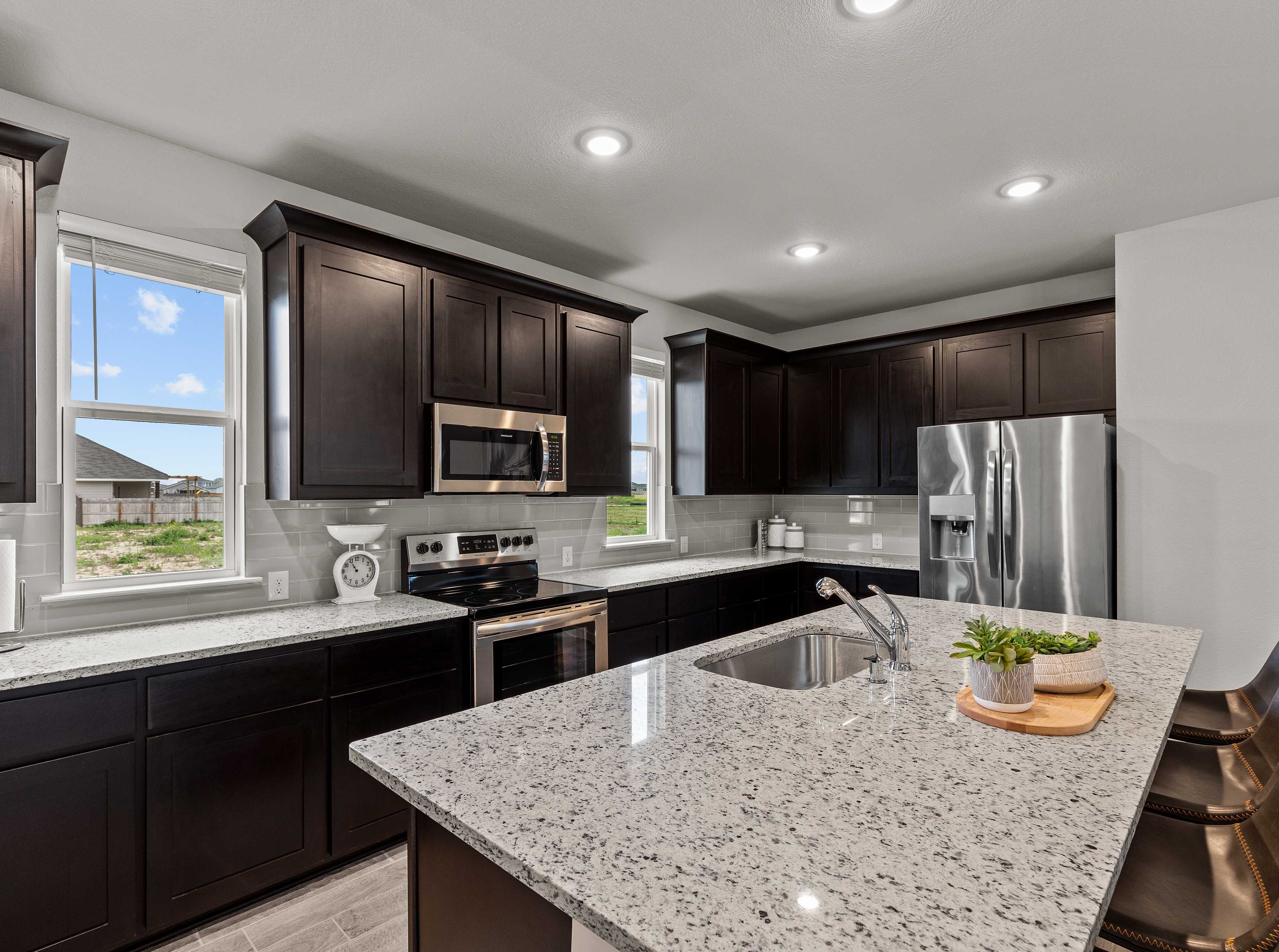 Modern kitchen with dark cabinets, granite island, stainless steel appliances at Hannah Heights in Seguin, Texas