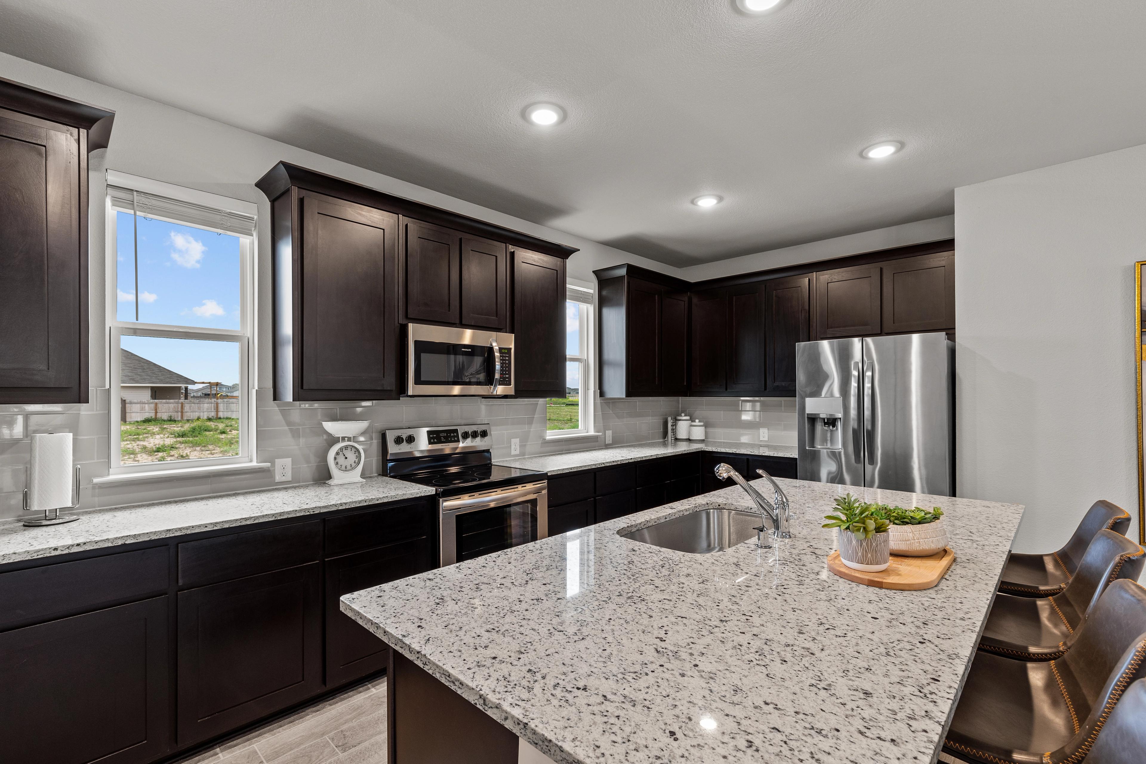 Spacious modern kitchen with espresso cabinets, white quartz island, stainless appliances at Hannah Heights, Seguin TX by Davidson Homes