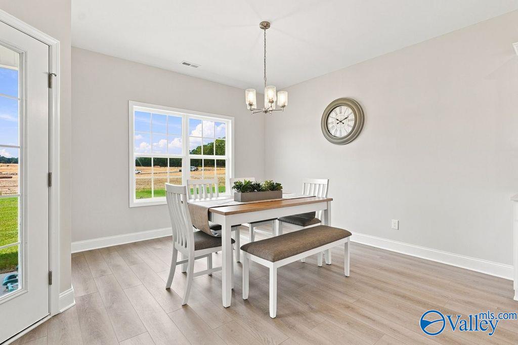 Bright dining area with wood-look flooring, chandelier, and bench seating in Davidson Homes The Harrison, Hartselle, Alabama