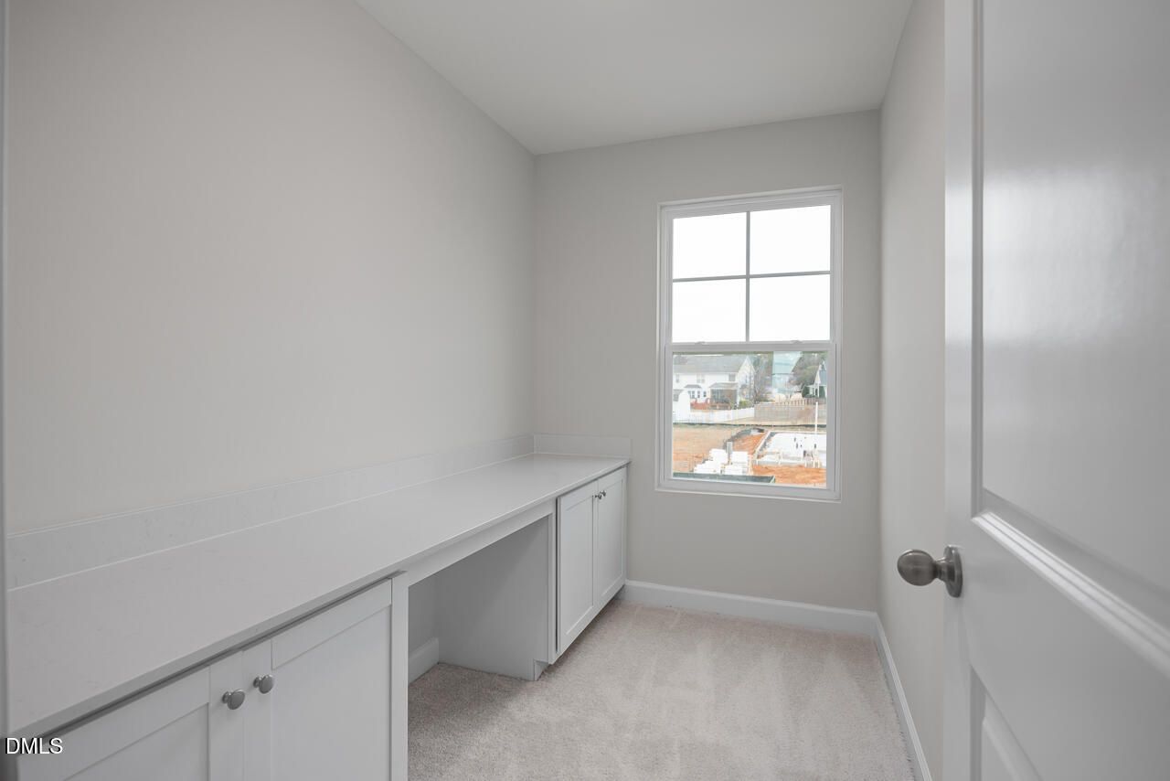 Cozy home office with built-in desk, cabinets, and large window in The Gavin B by Davidson Homes, Gregory Village, Lillington, NC