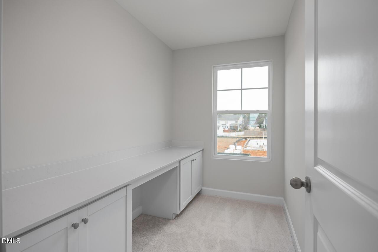 Cozy home office with built-in desk, cabinets, and large window in The Gavin B by Davidson Homes, Gregory Village, Lillington, NC